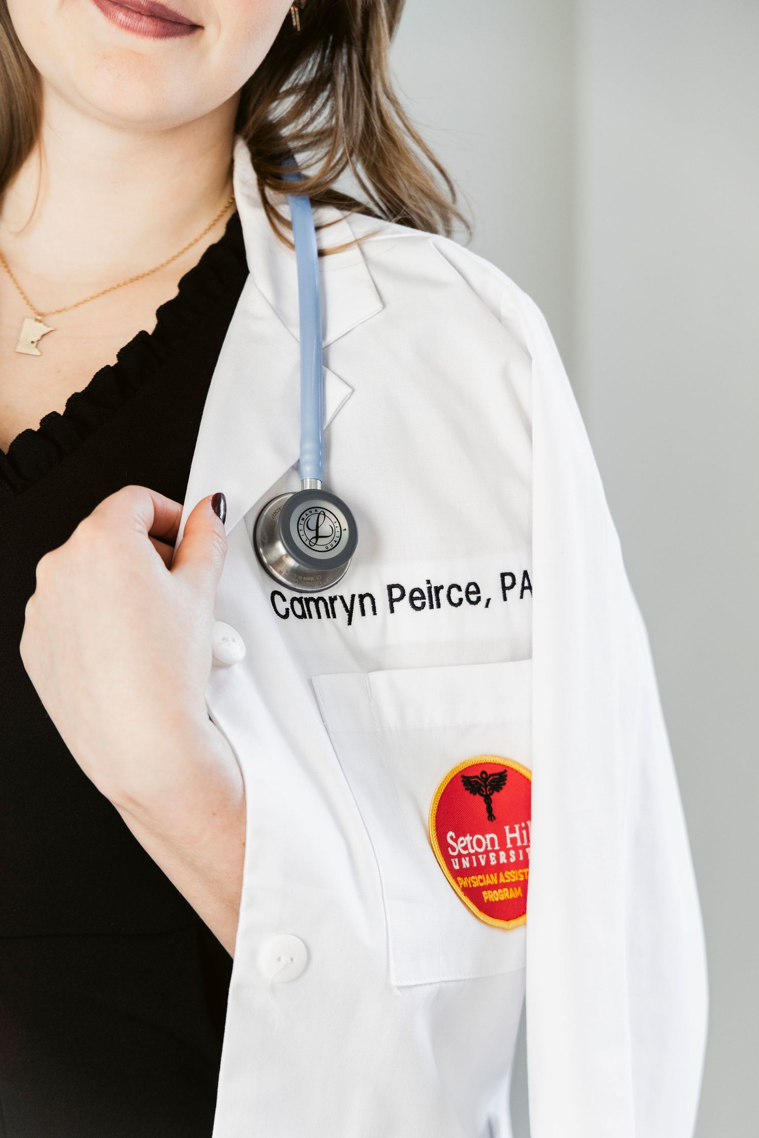 Close-up of medical professional's white coat with name badge and stethoscope.