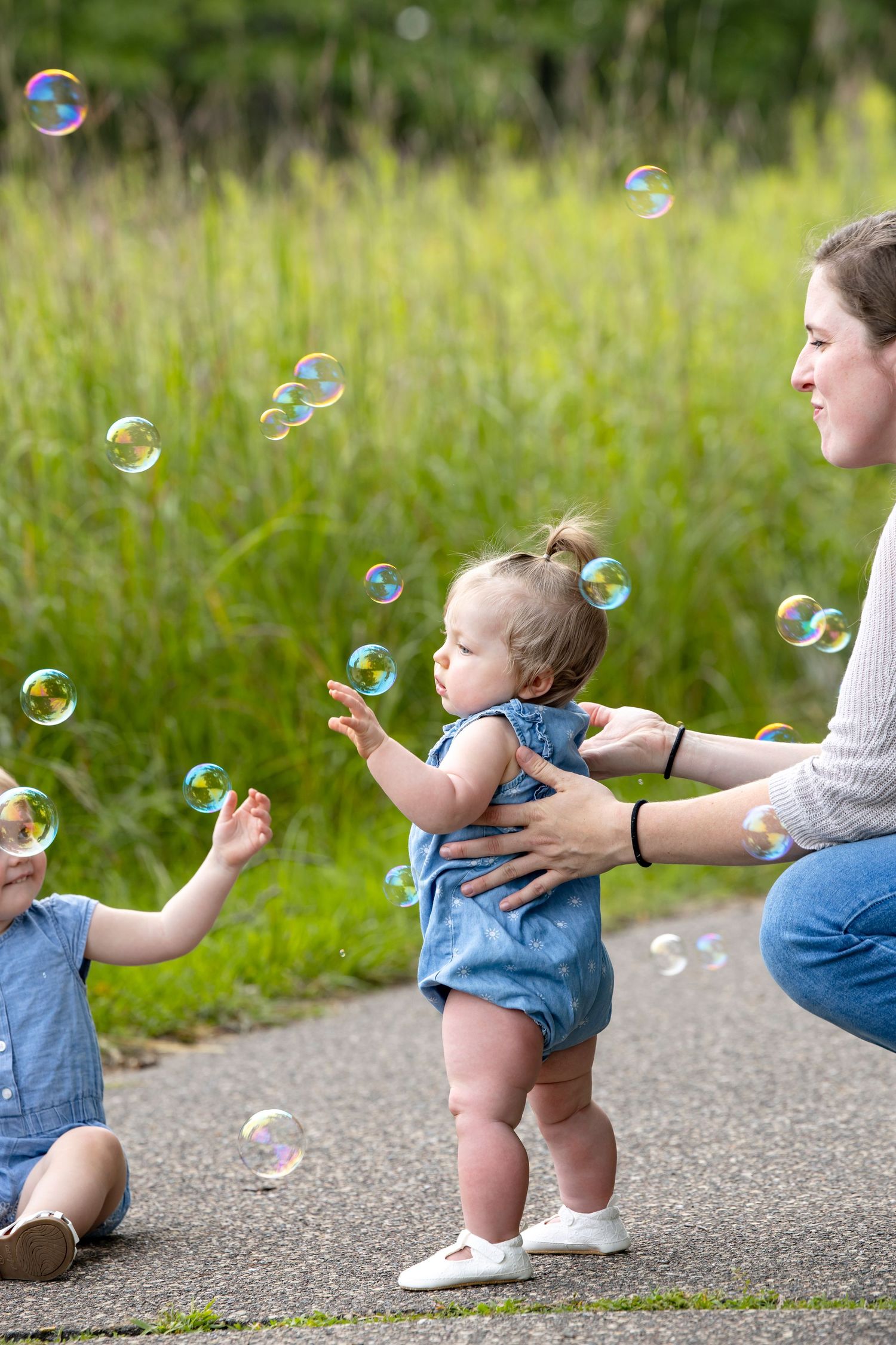 Sequence showing a small child in denim reaching for bubbles on a path.