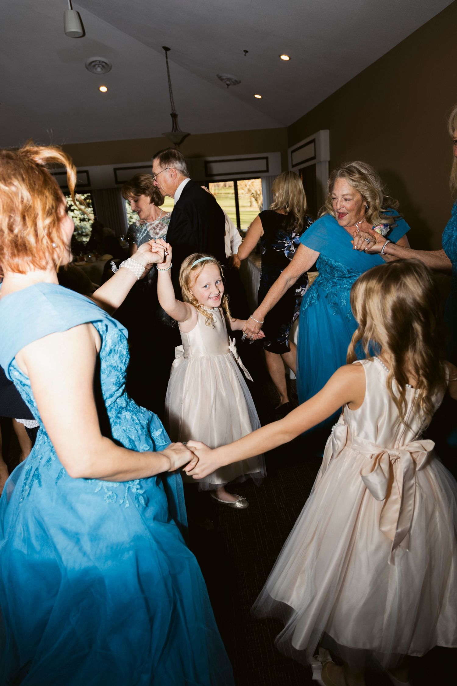 Wedding reception dance floor with guests in blue dresses and flower girl dresses.