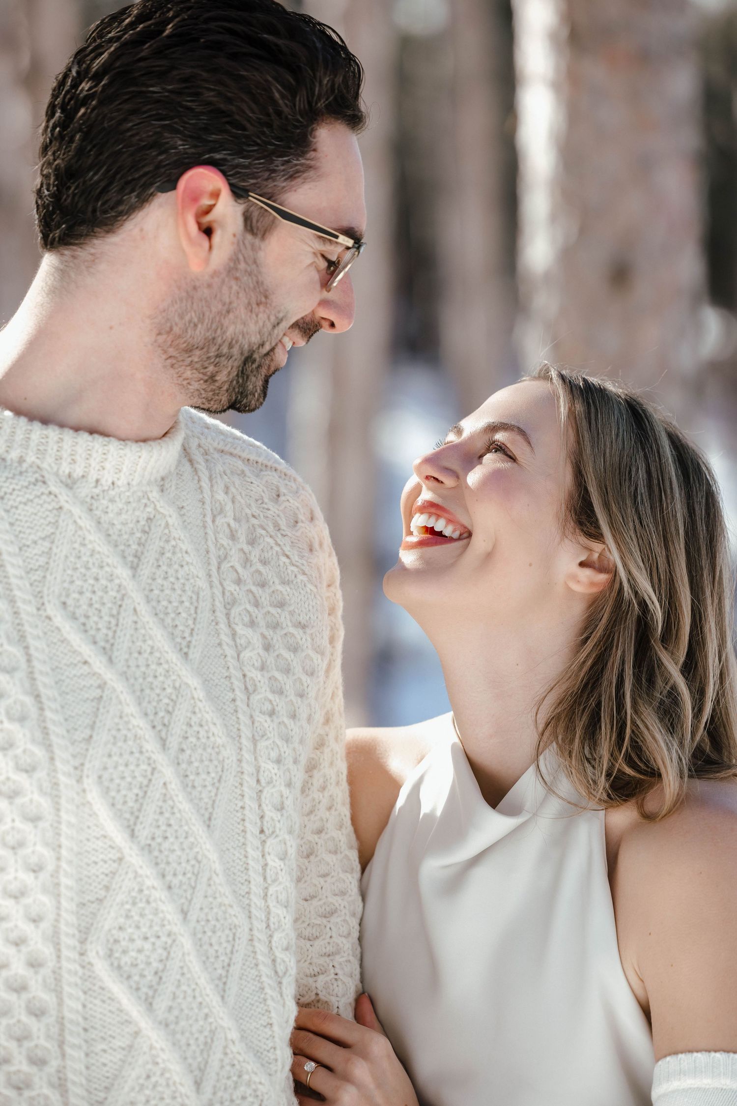 A candid moment of laughter between a couple during a winter photoshoot.