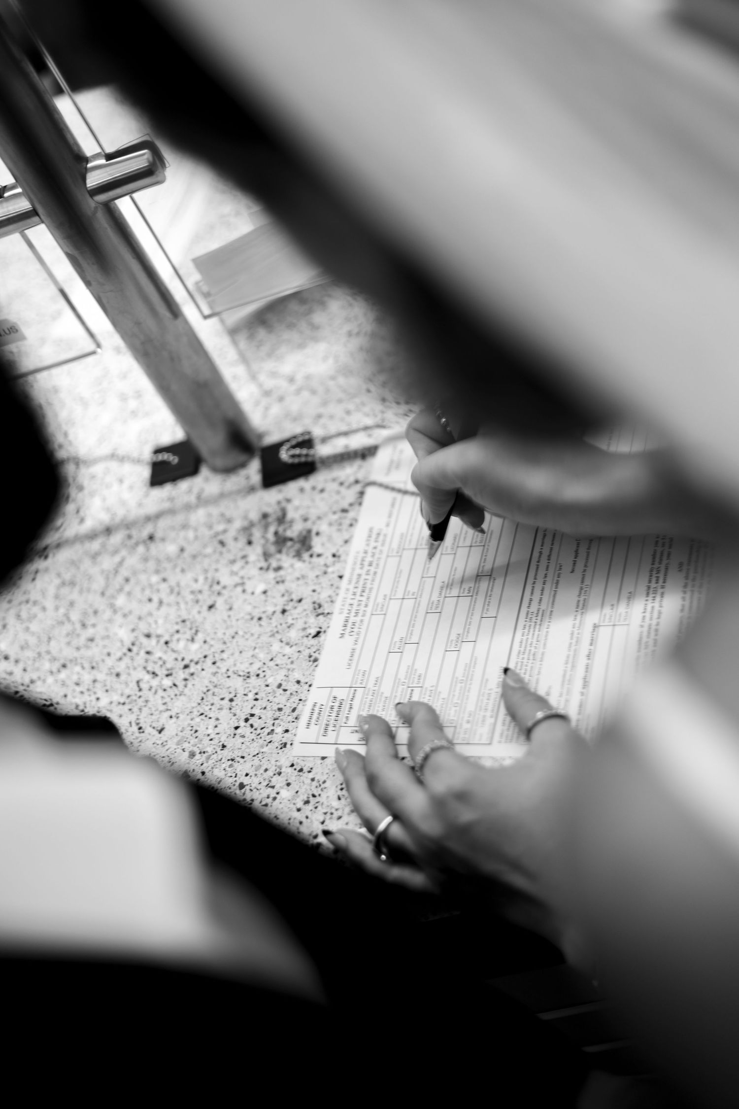 Close-up of hands writing on paper forms in black and white.