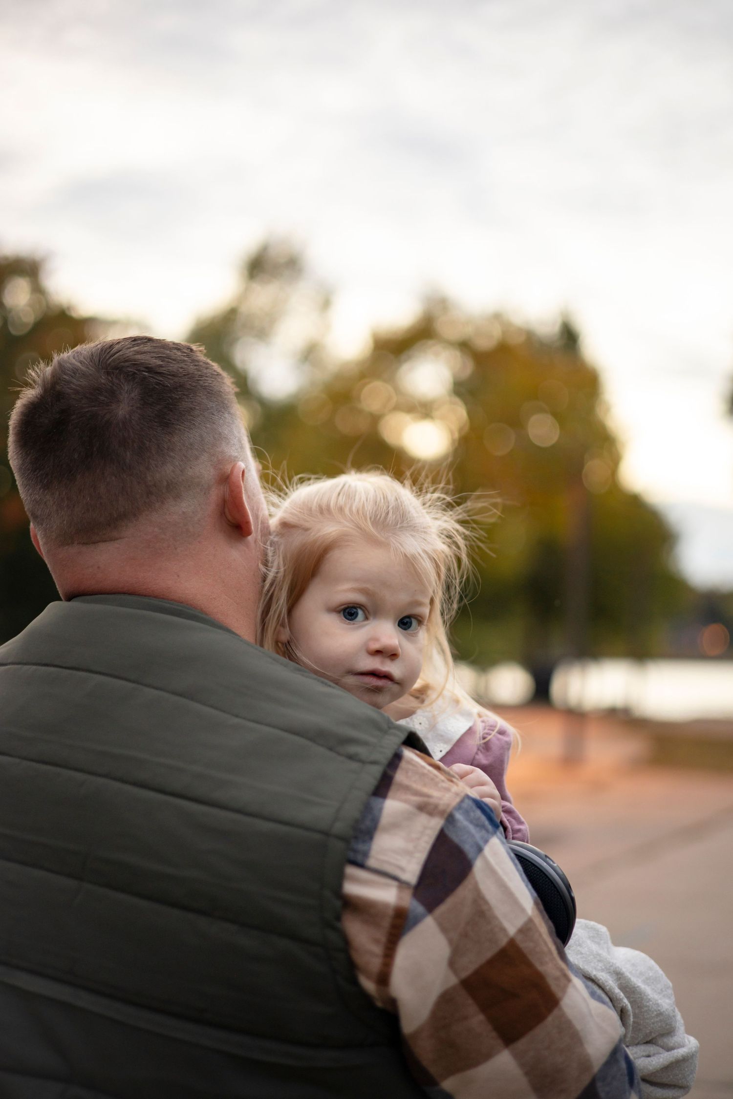A child is held against an overcast sky during a family photo session.