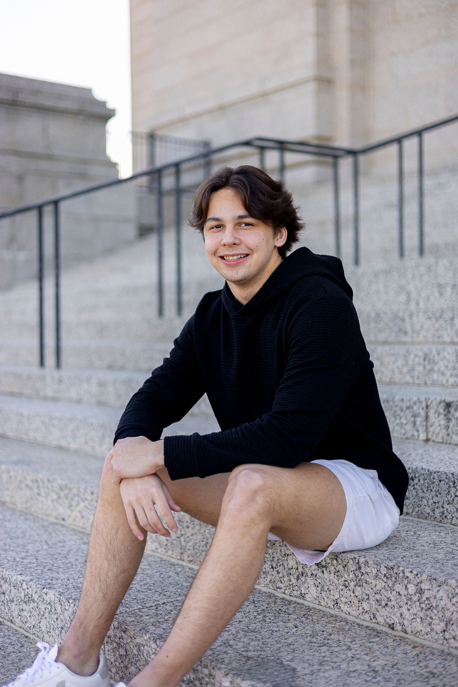 Person in black clothing sitting on concrete steps in a series of casual poses.