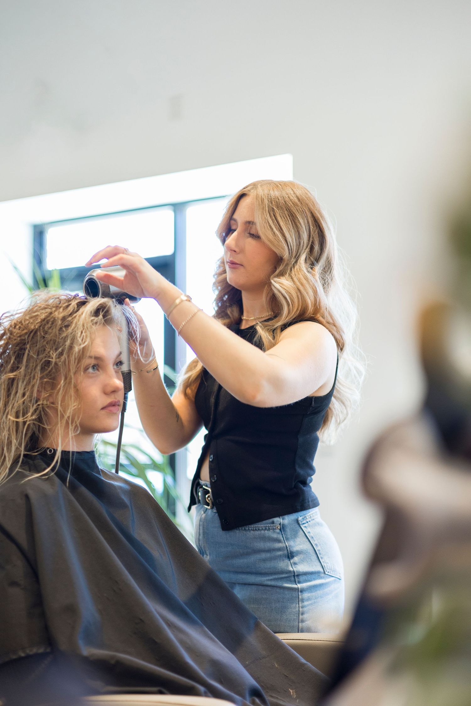 Hair stylist working on client's hair in modern salon setting.