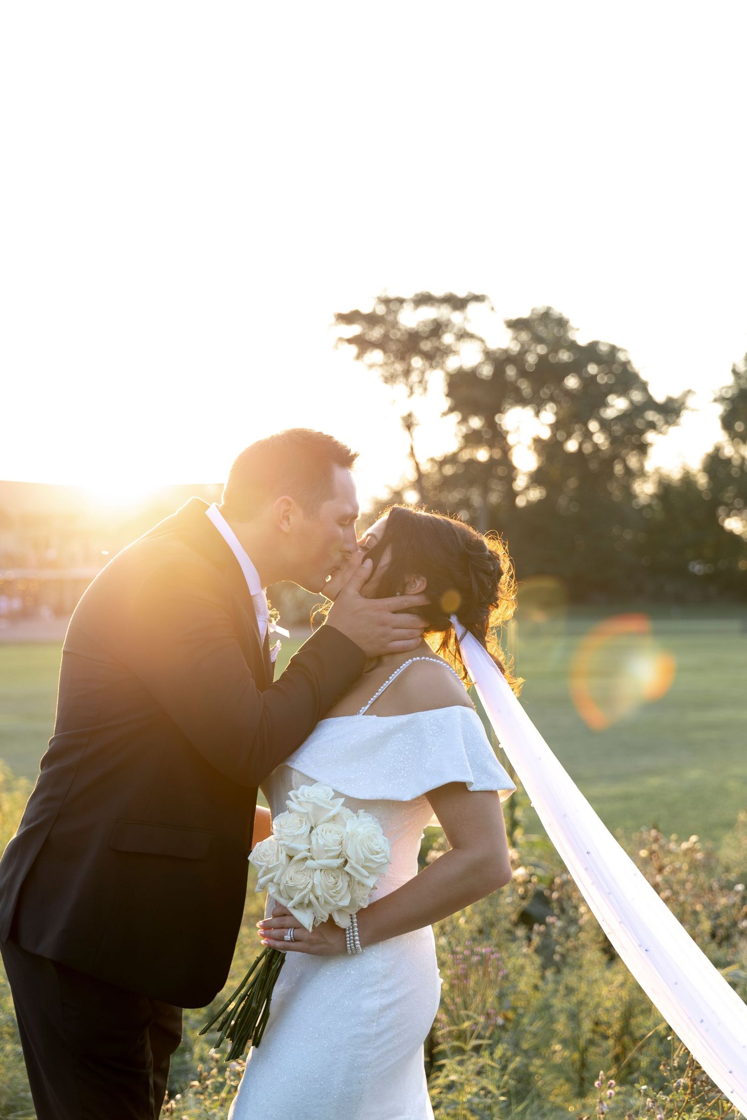 Romantic sunset wedding portrait in a golden field during magic hour.