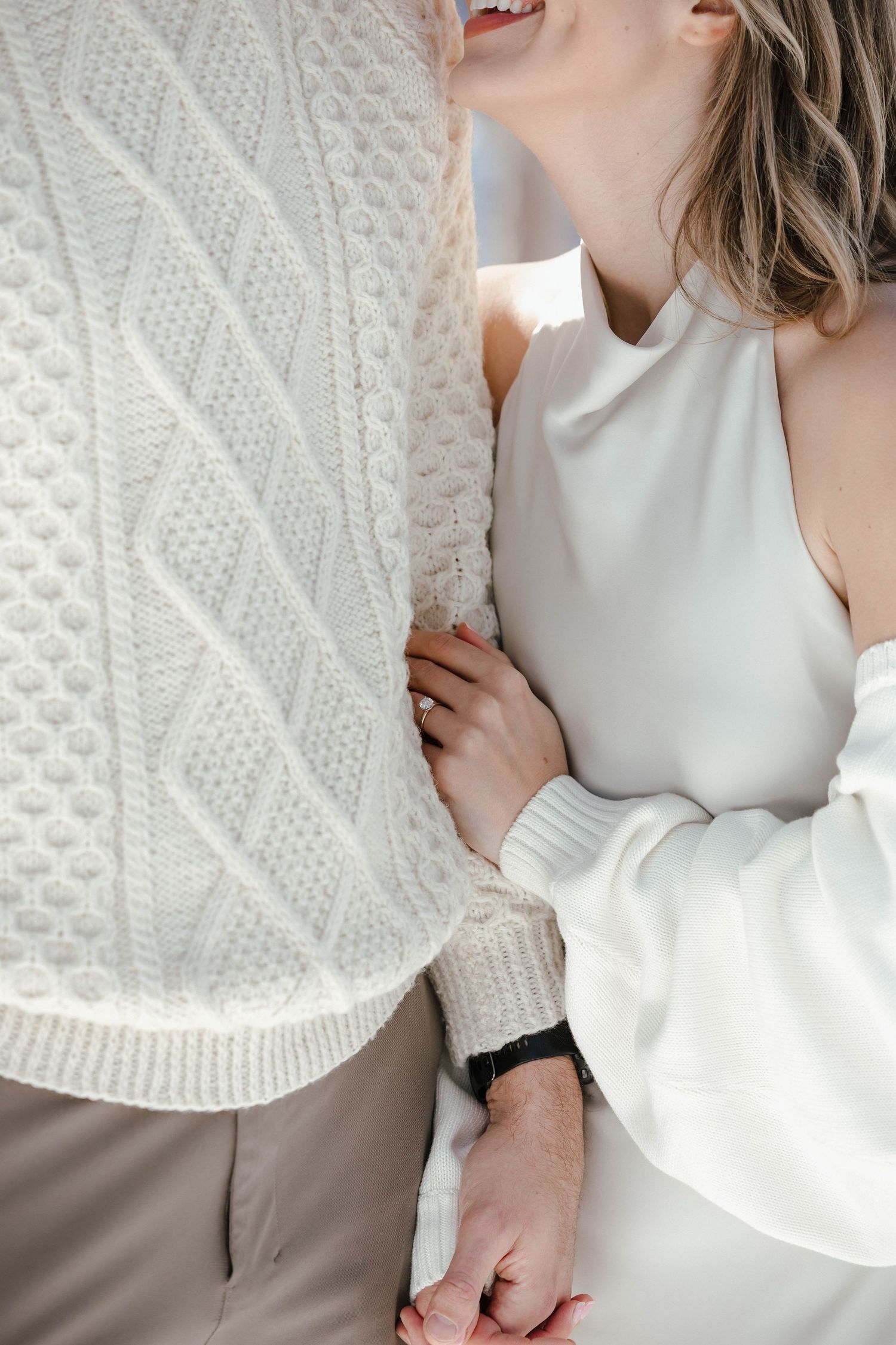 Couple sharing laughter while wearing coordinated winter outfits.