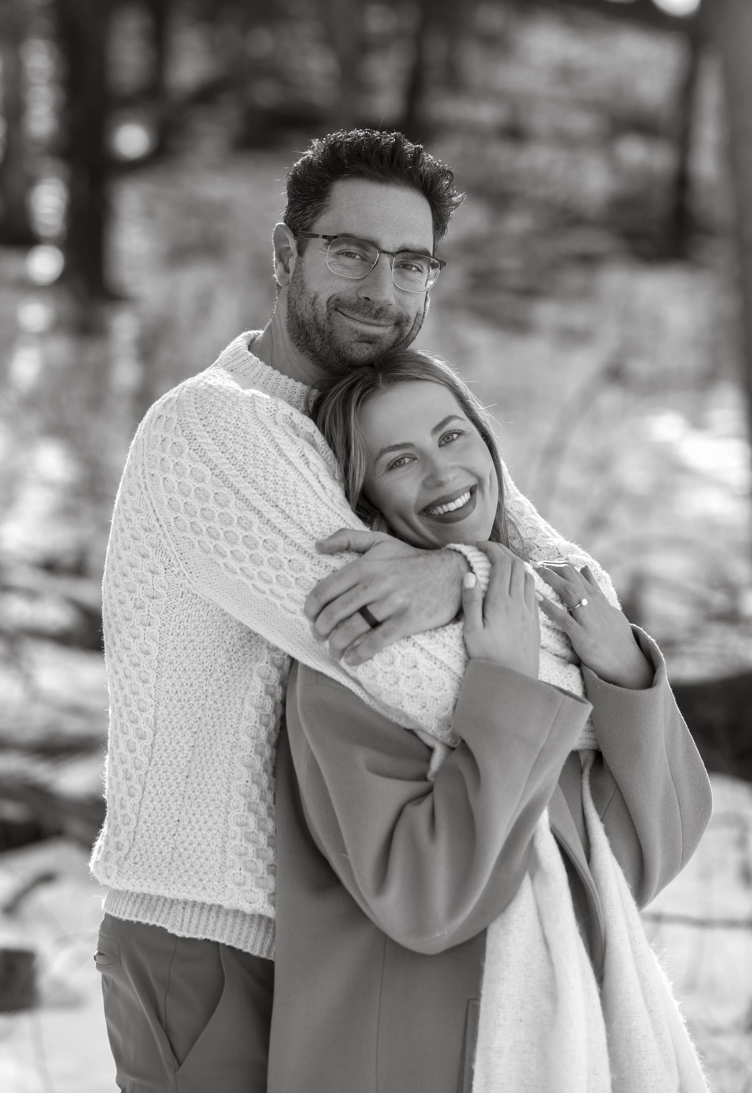 A joyful embrace captured in black and white showing affection between a couple in winter clothing.
