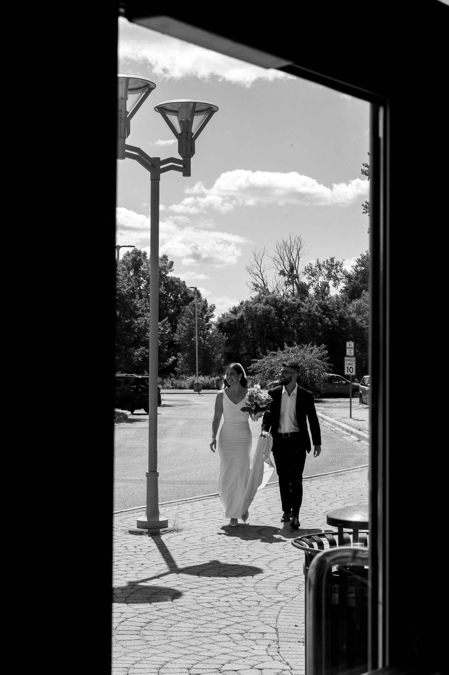 A silhouetted view through a doorway of a couple walking on a sunny day.