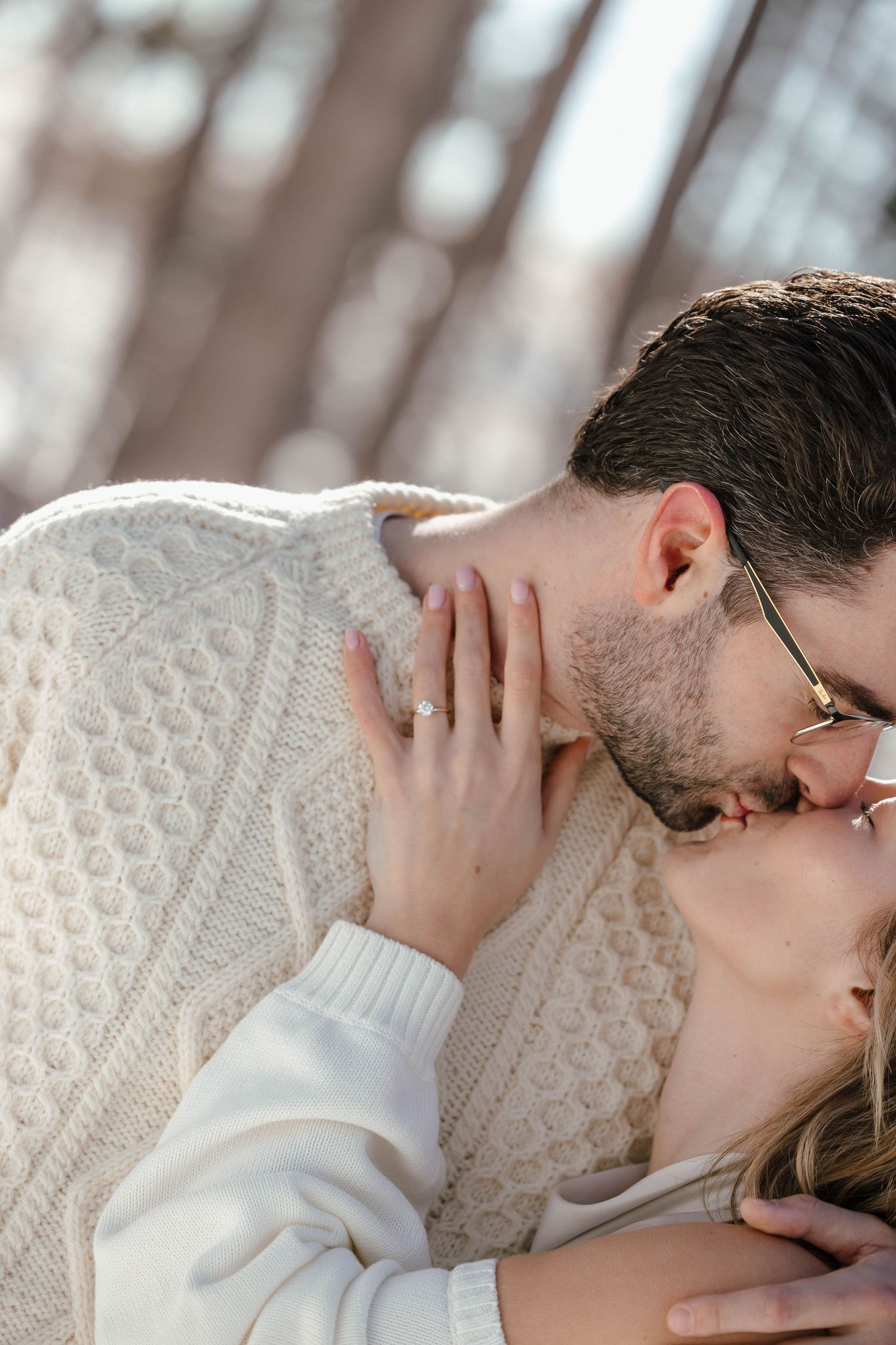 Intimate close-up of couple sharing a tender moment in winter forest setting.