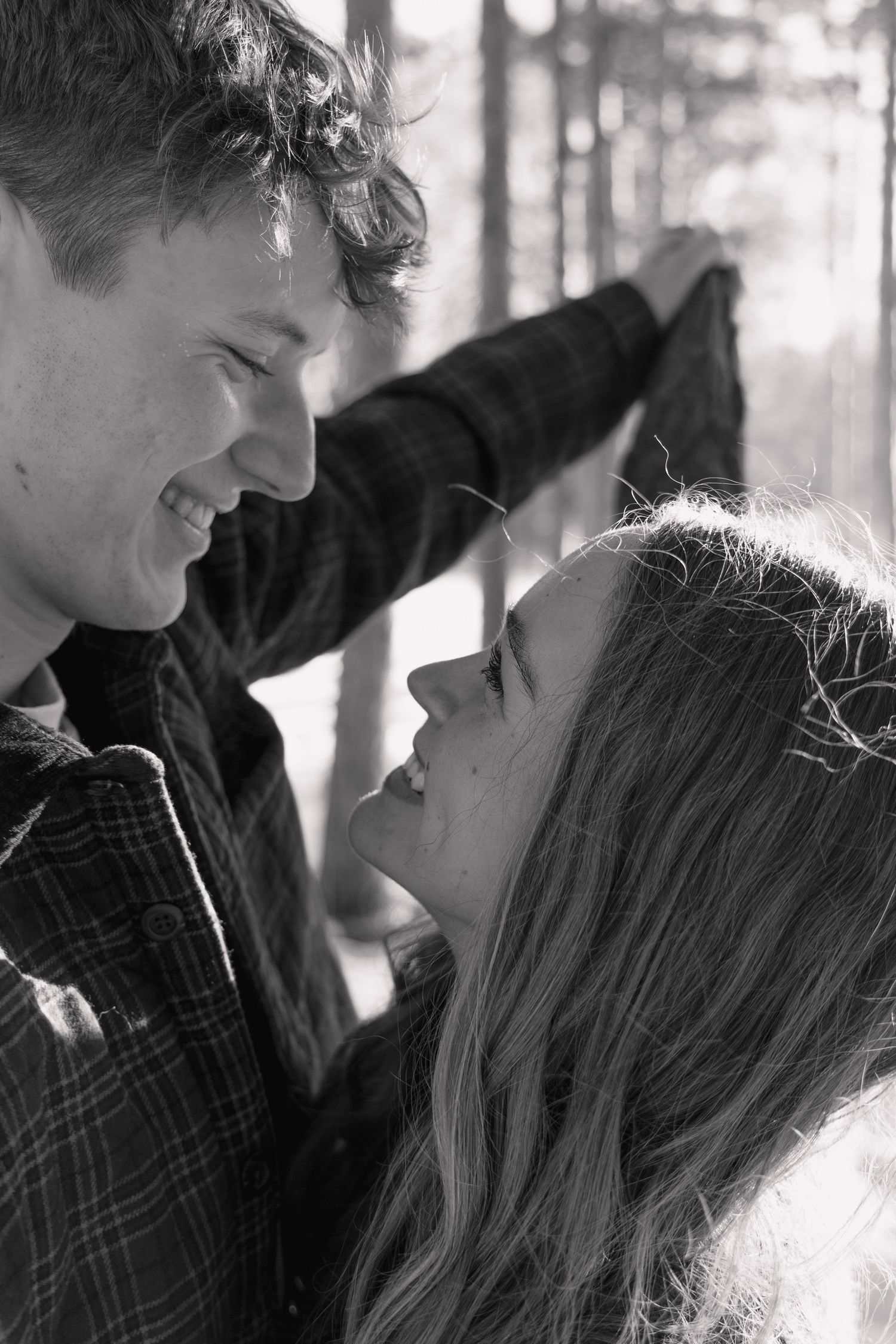 Close-up black and white portrait of couple sharing intimate moment in forest.
