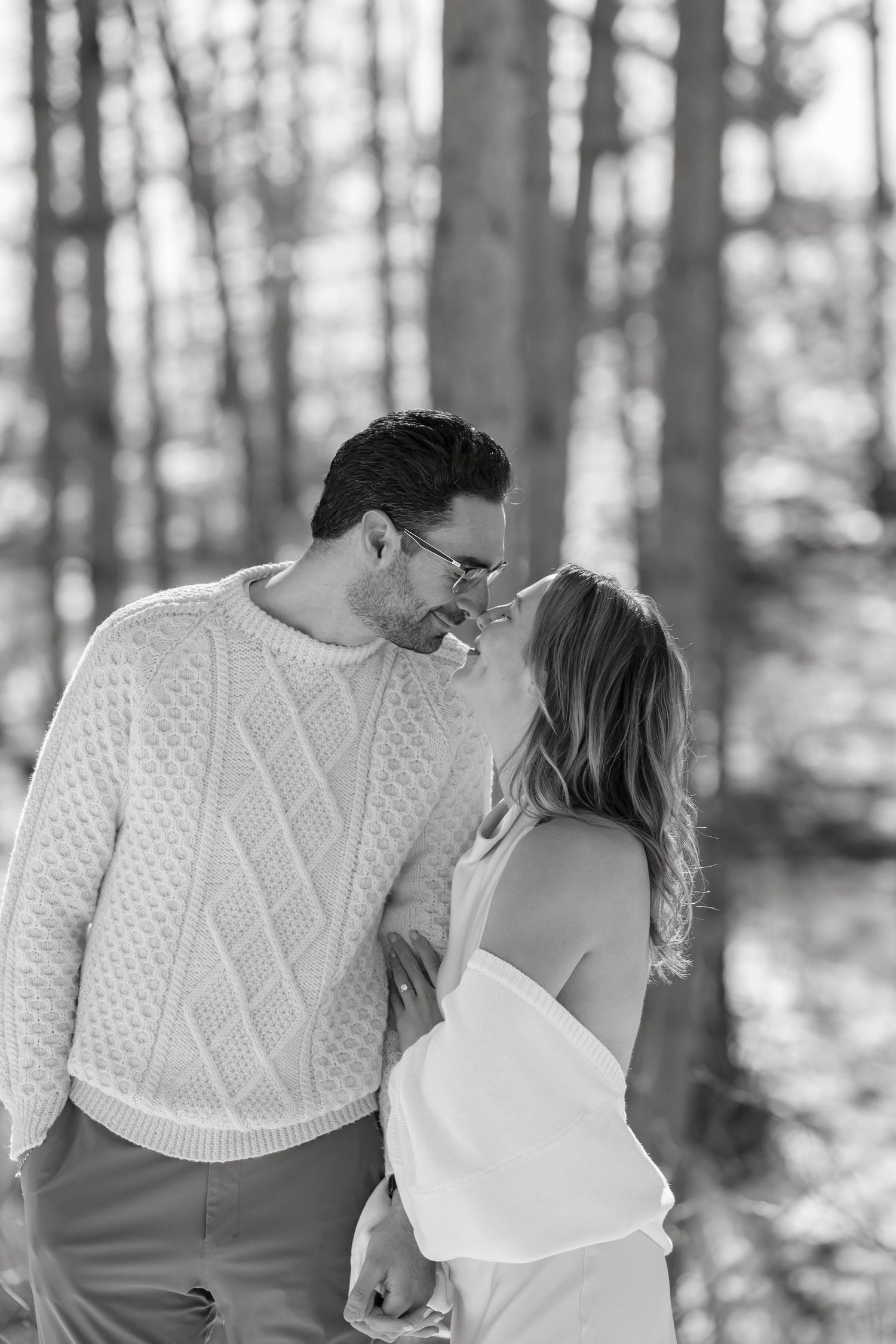 Couple in winter attire sharing an intimate moment in a snowy forest.