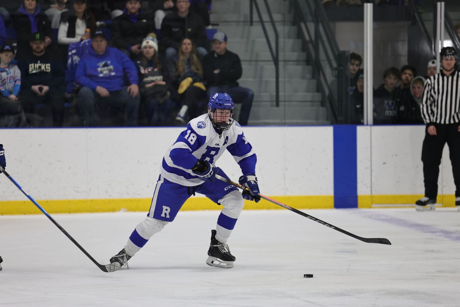 Hockey players in blue jerseys competing for puck control during game.