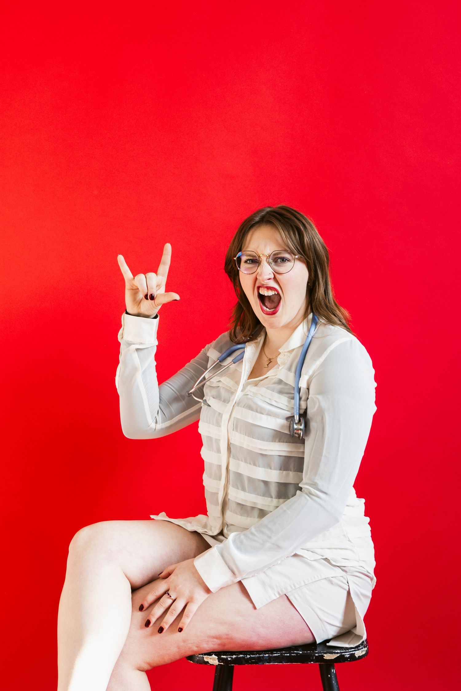 Energetic portrait session with person in white outfit against red background.