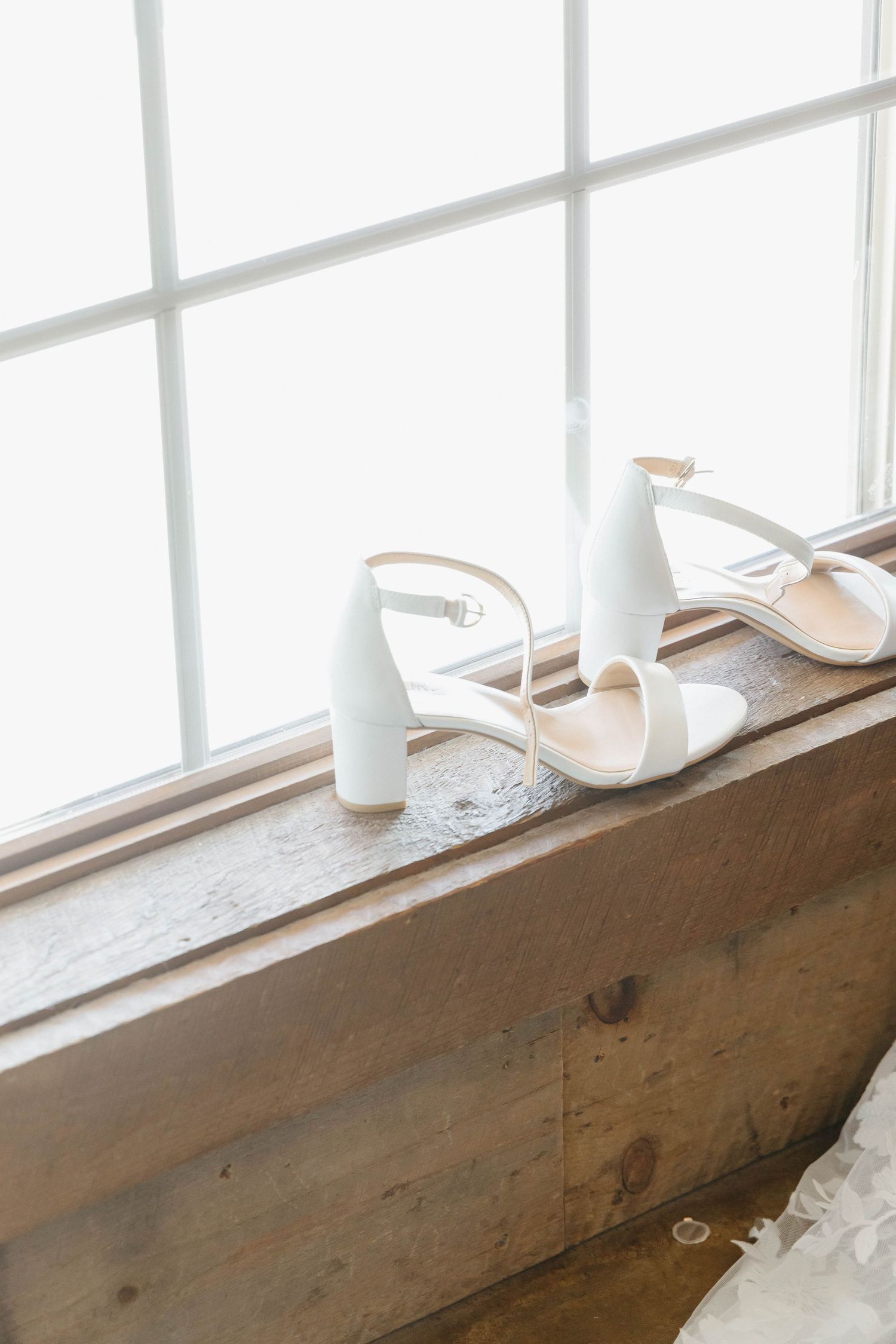 White milk bottles and decorative items arranged on a rustic wooden windowsill.