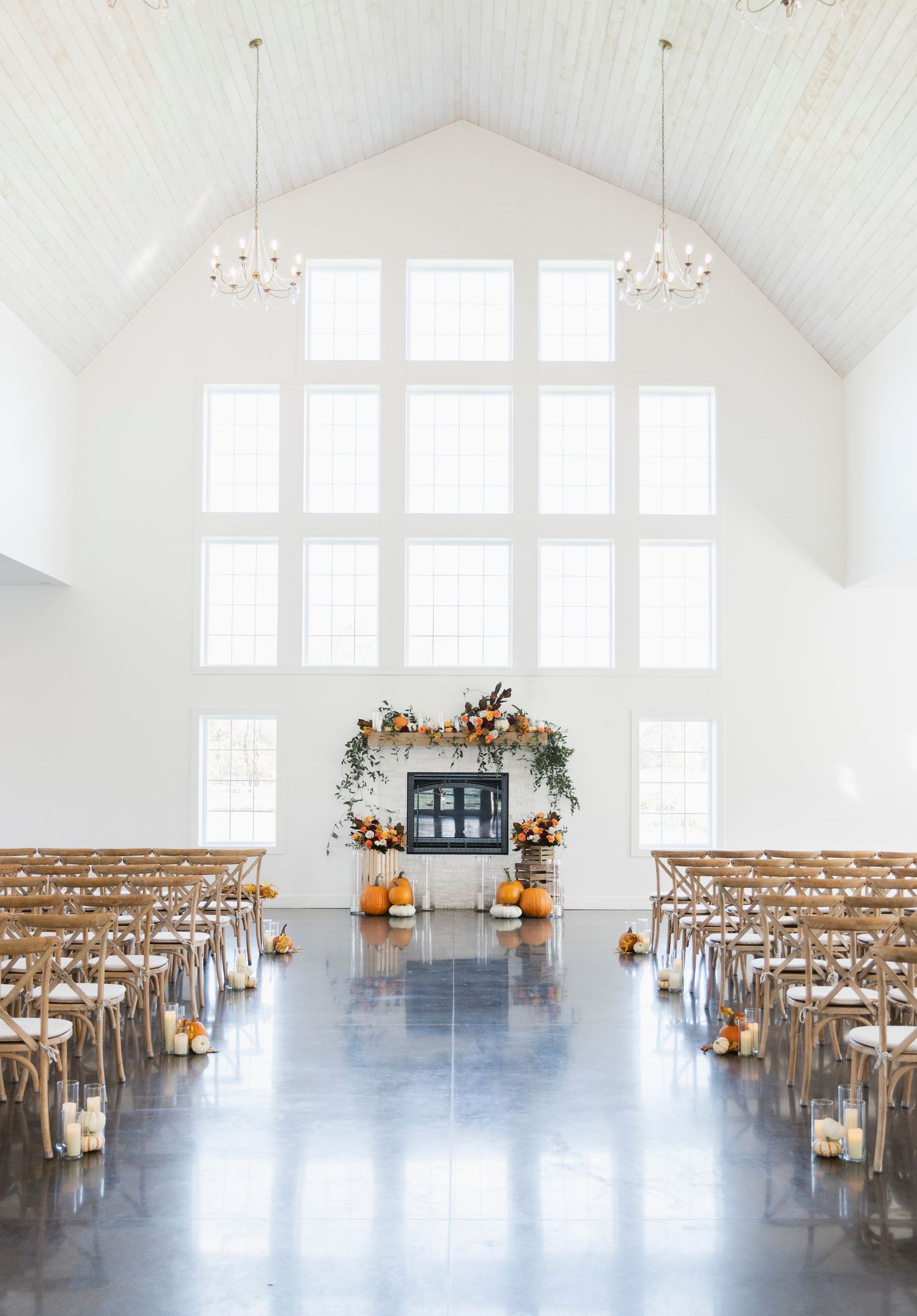 A bright white wedding chapel interior with wooden chairs and floral decorations.