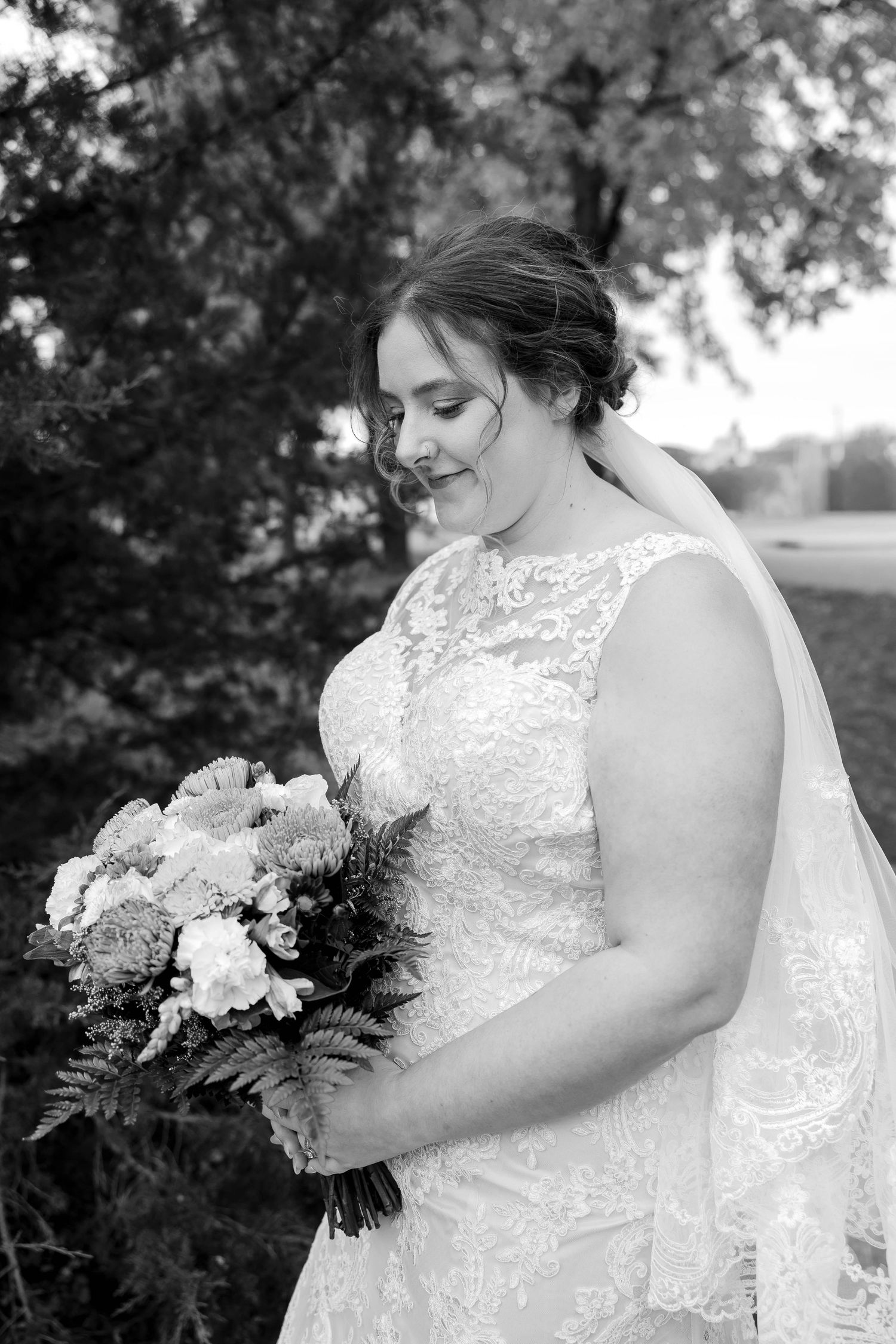 Black and white portrait of someone holding a beautiful wedding bouquet outdoors.