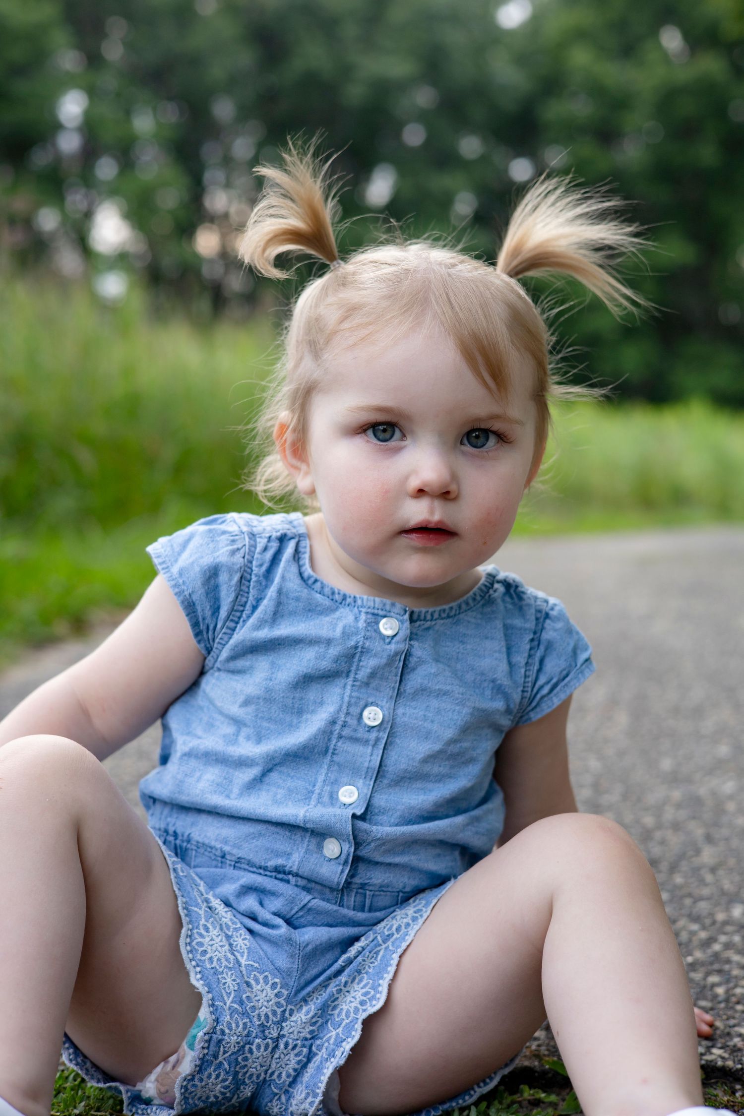Progressive shots of a child in a blue denim dress sitting on a path.