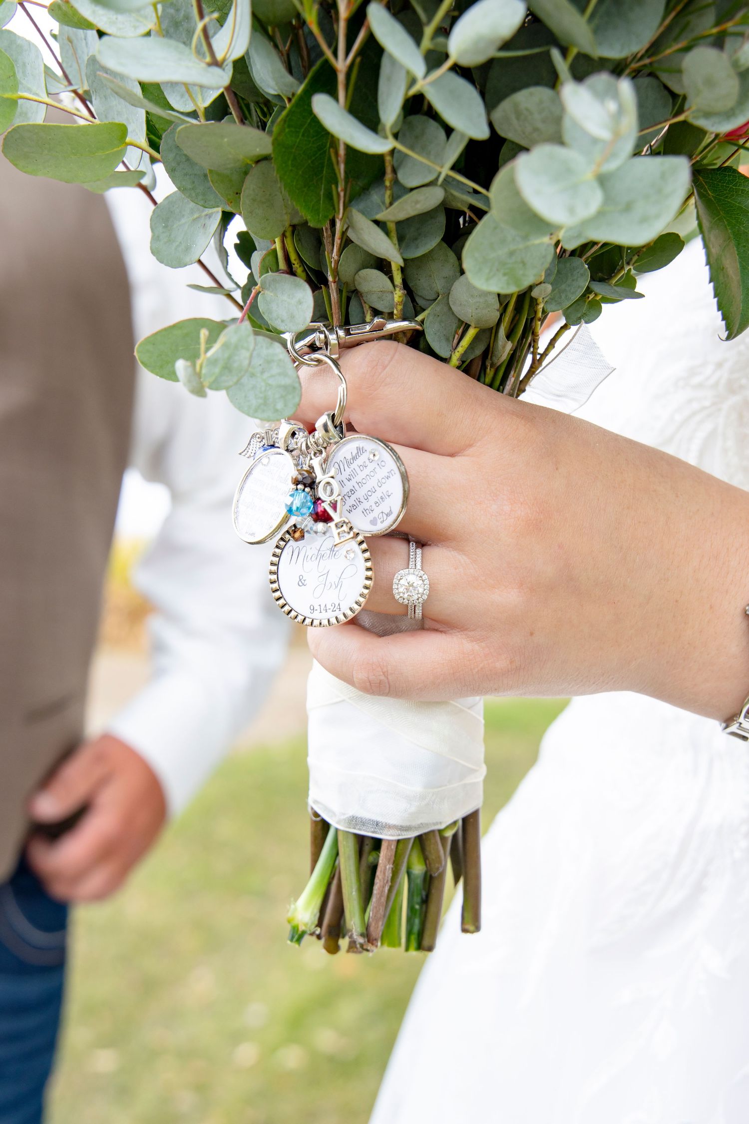 Wedding bouquet with eucalyptus leaves held by hands wearing ornate jewelry.