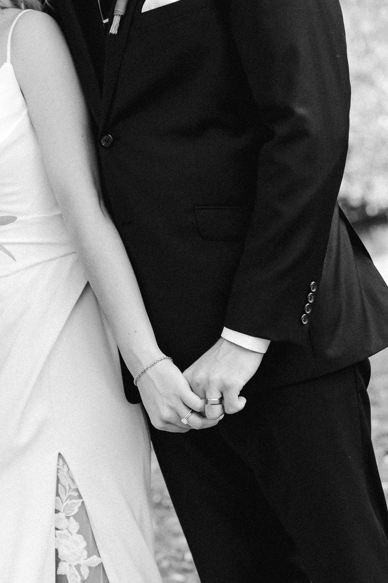 Black and white photo showing wedding couple holding hands during ceremony.