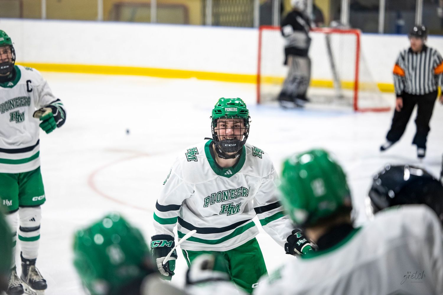 Hockey players in green jerseys position themselves during gameplay on the ice.