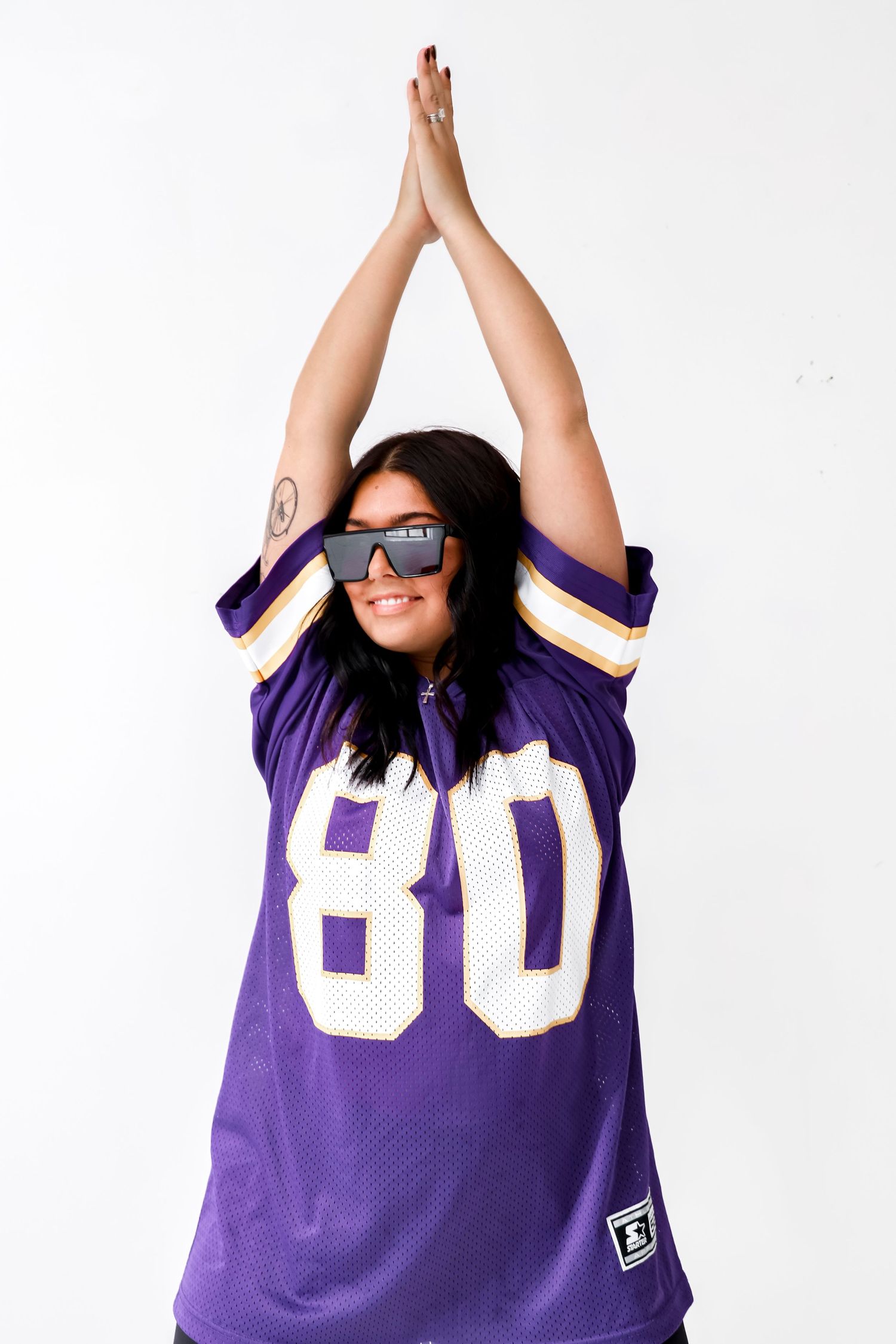 Person wearing purple sports jersey with number 80 raising arms in celebration.