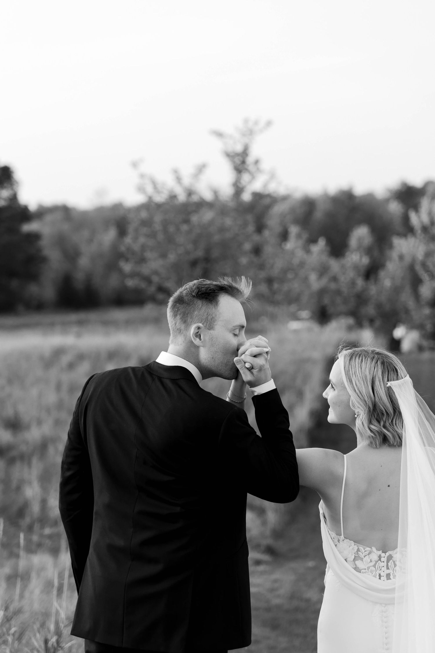 Black and white portrait of couple sharing intimate moment in outdoor setting.