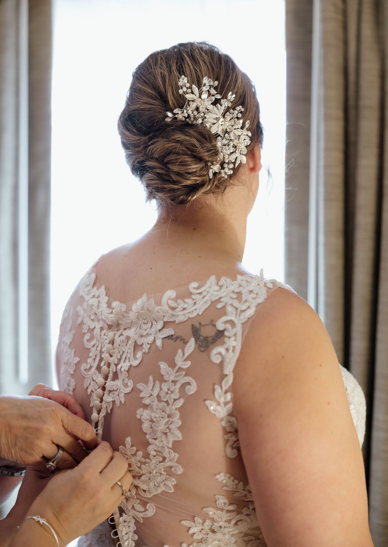 Close-up of intricate lace detail and pearl hair accessory on an elegant wedding dress.