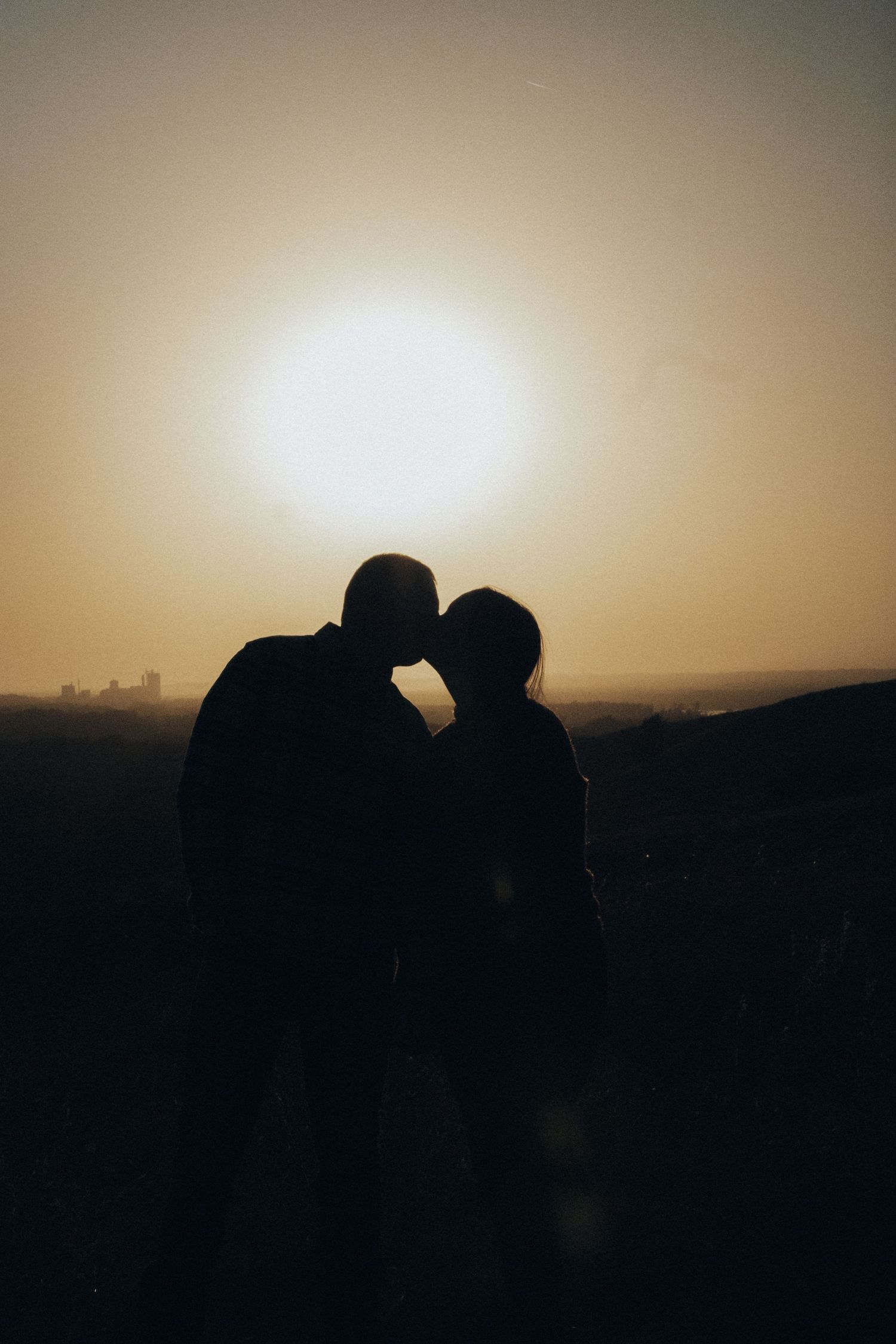 Silhouettes of a couple against a golden sunset sky.