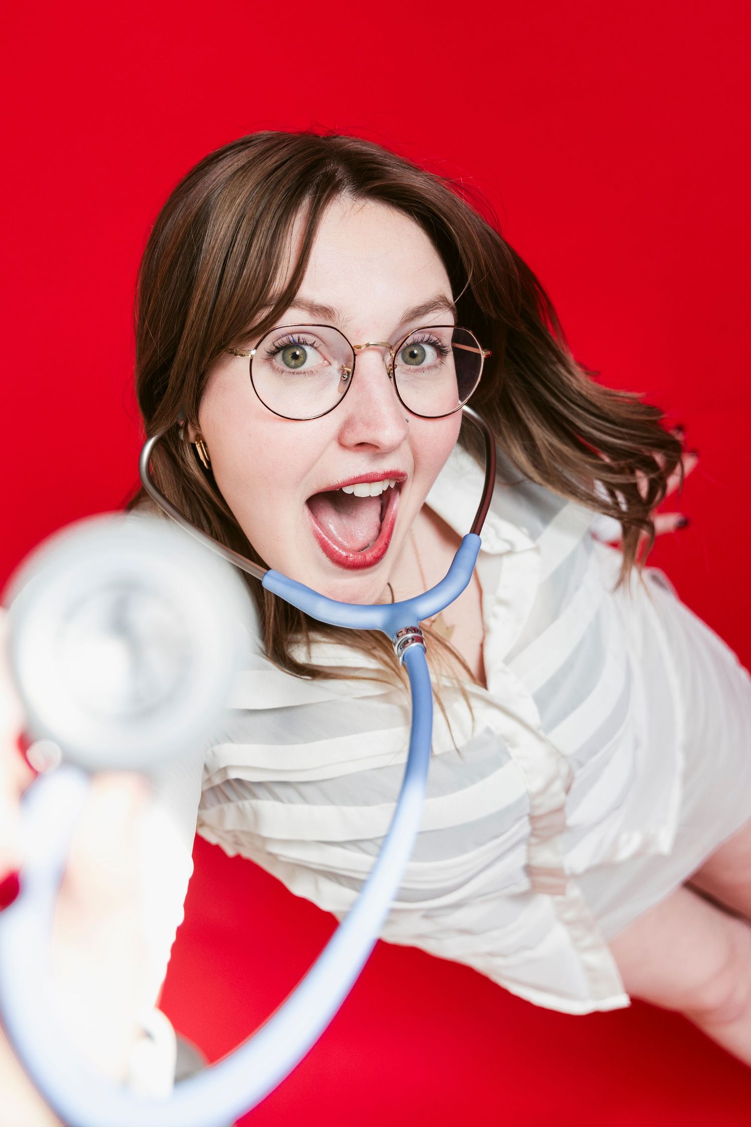 A playful portrait against a bright red background featuring glasses and a blue tie.