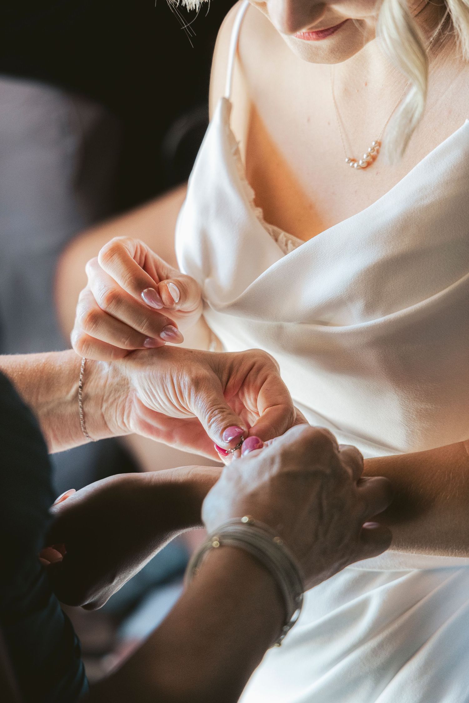 Close-up of hands adjusting jewelry or accessories on wedding dress.