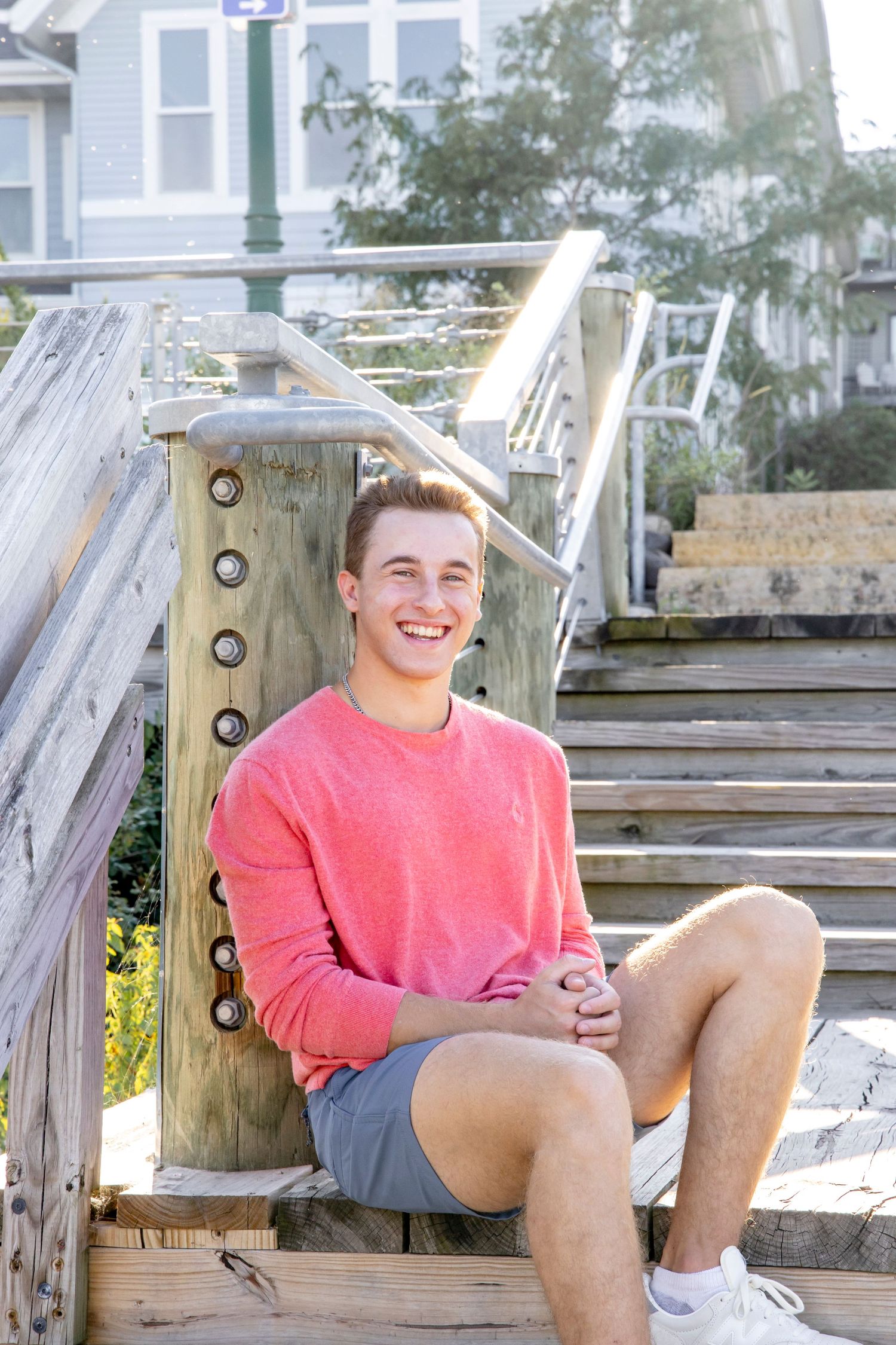 Person in coral shirt lounges on wooden beach boardwalk during summer.