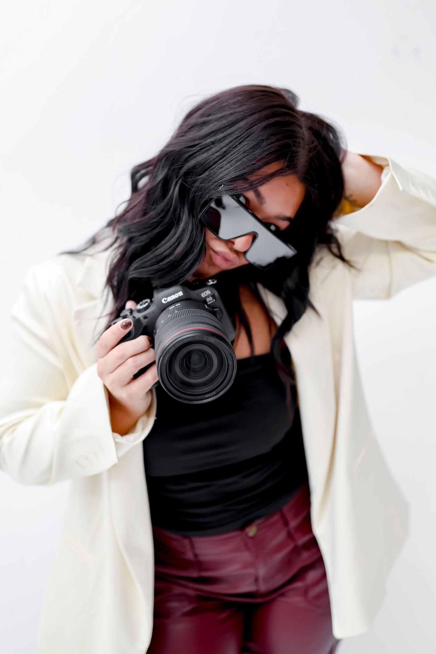 Person in white jacket holding professional camera against white background.