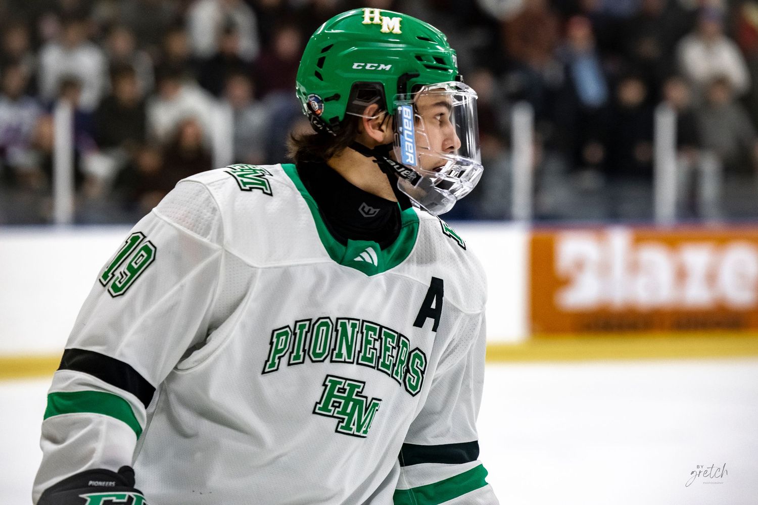 Ice hockey players in green and white uniforms compete during a fast-paced game.