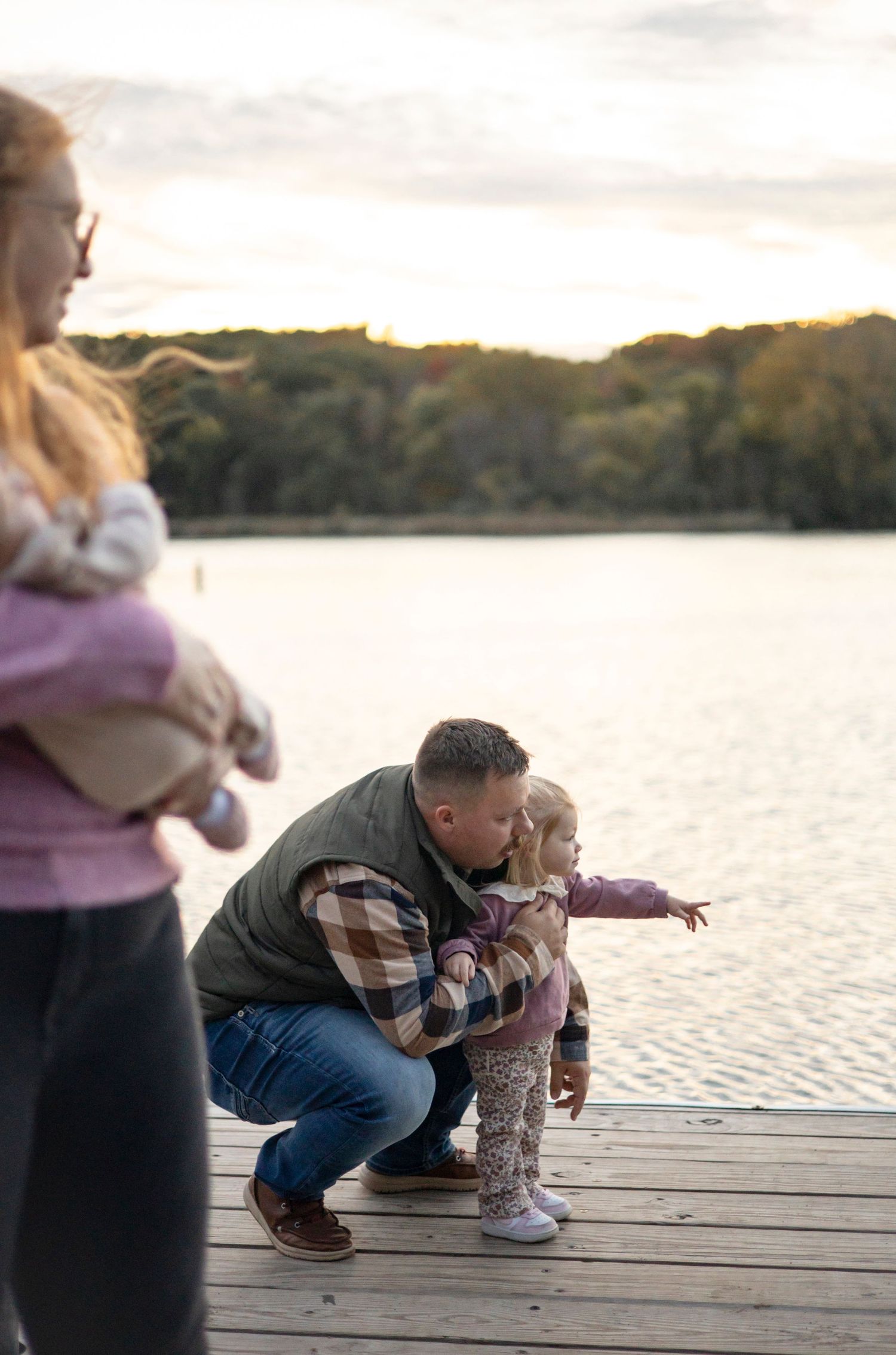 Intimate family moments captured on a lakeside dock during golden hour.