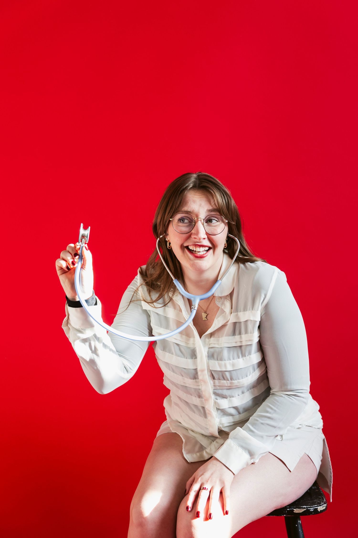 Person in white outfit making expressive poses against vibrant red backdrop.