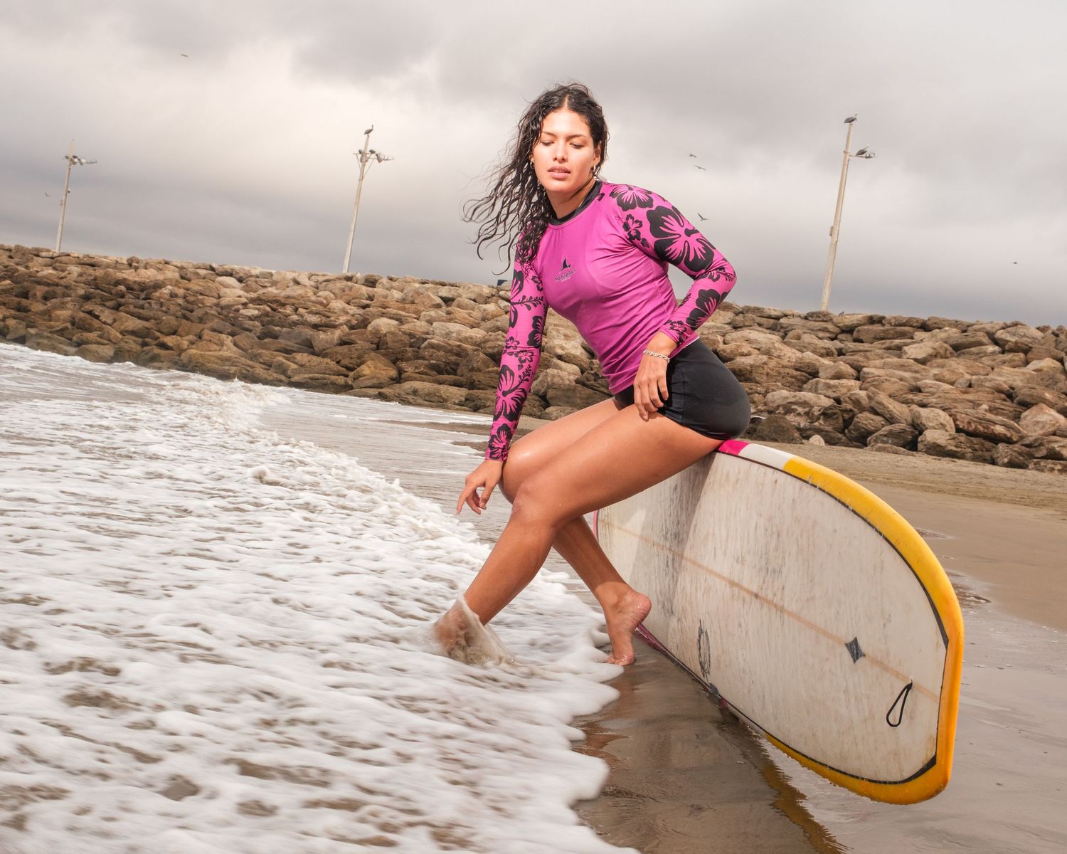 Surfboard action sequence at beach with waves crashing against rocks.