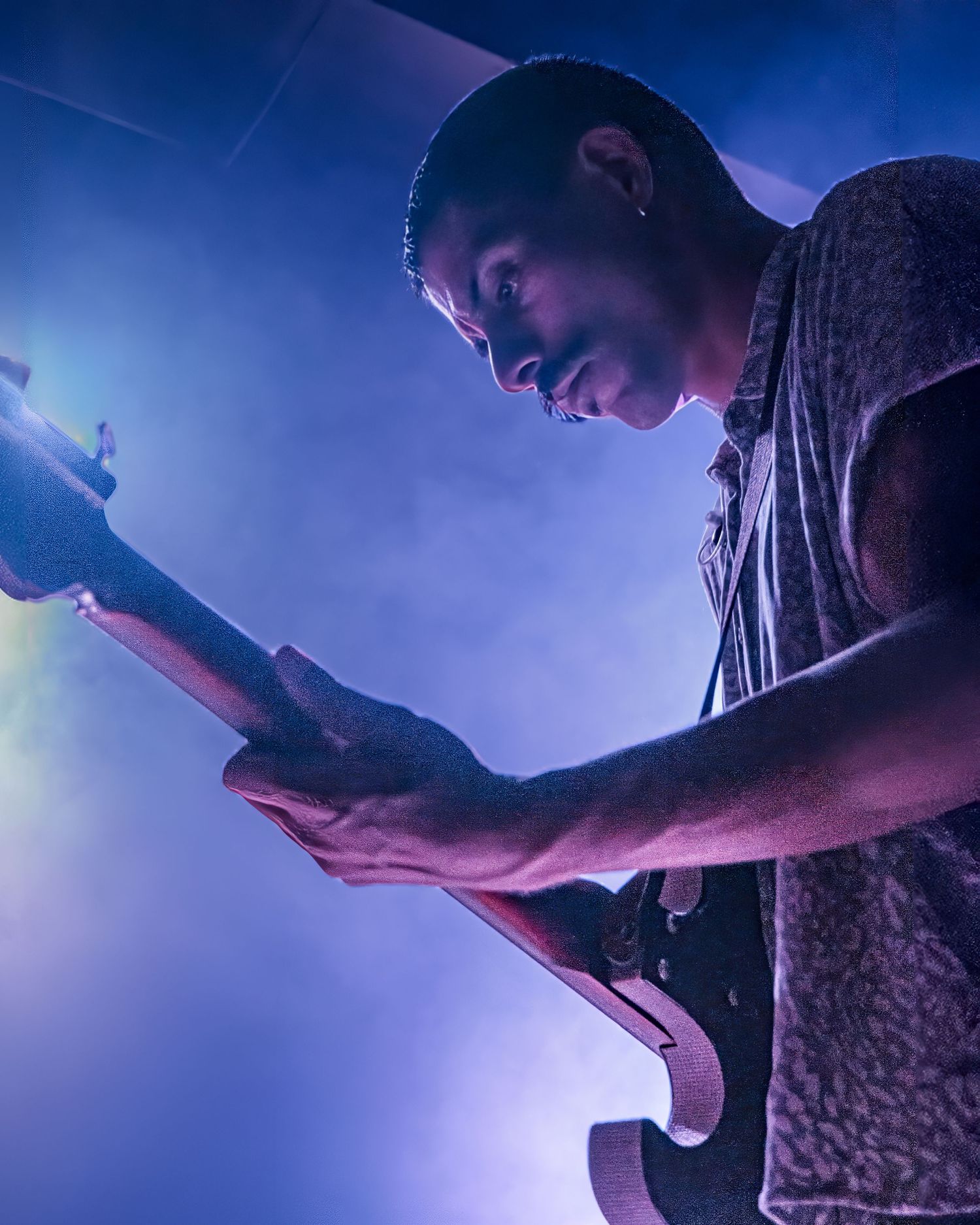 Musicians performing on stage with dramatic blue lighting and fog effects.