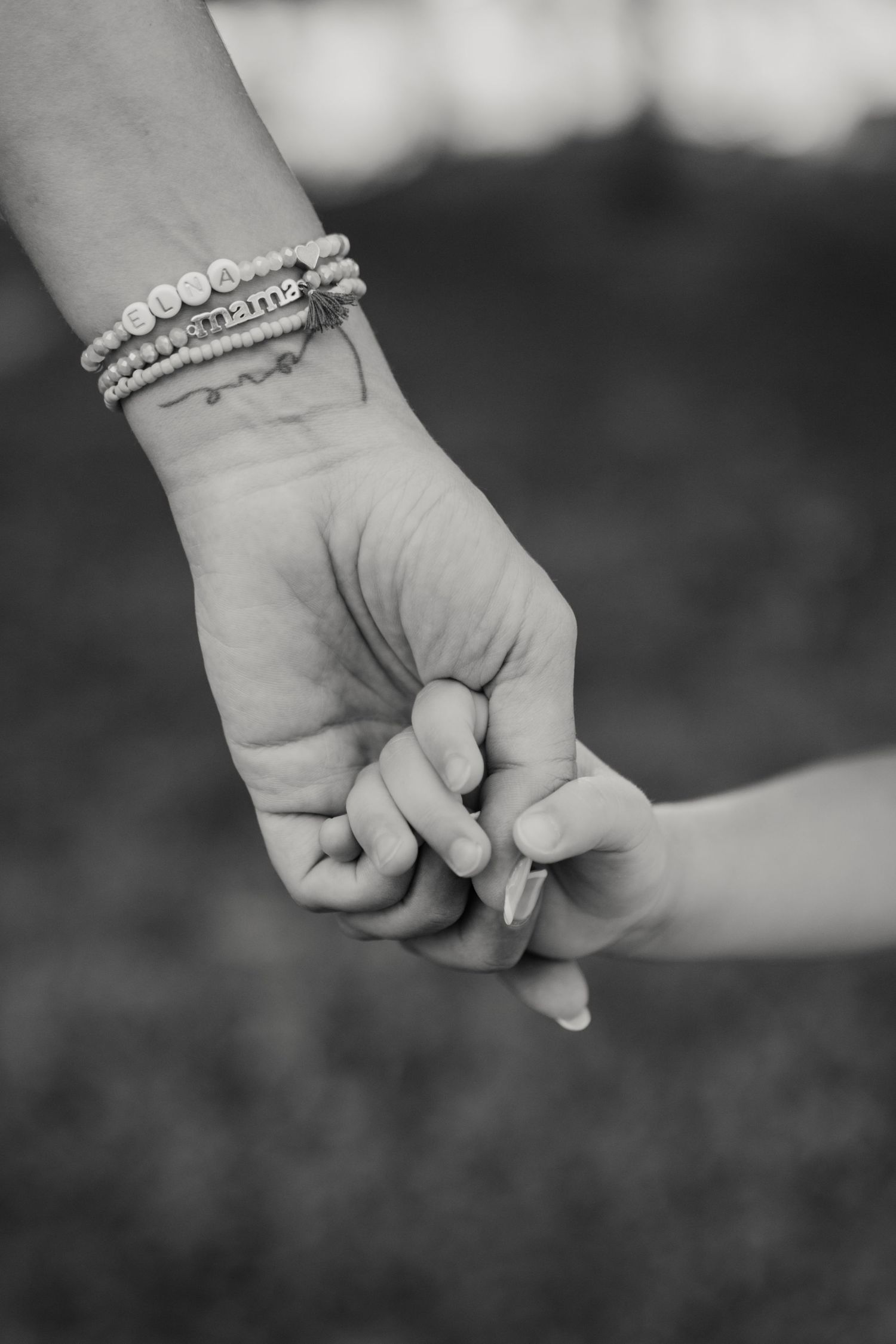 Detalle en blanco y negro de la mano de un padre sujetando la mano de su hija en sesión familiar en Tarragona