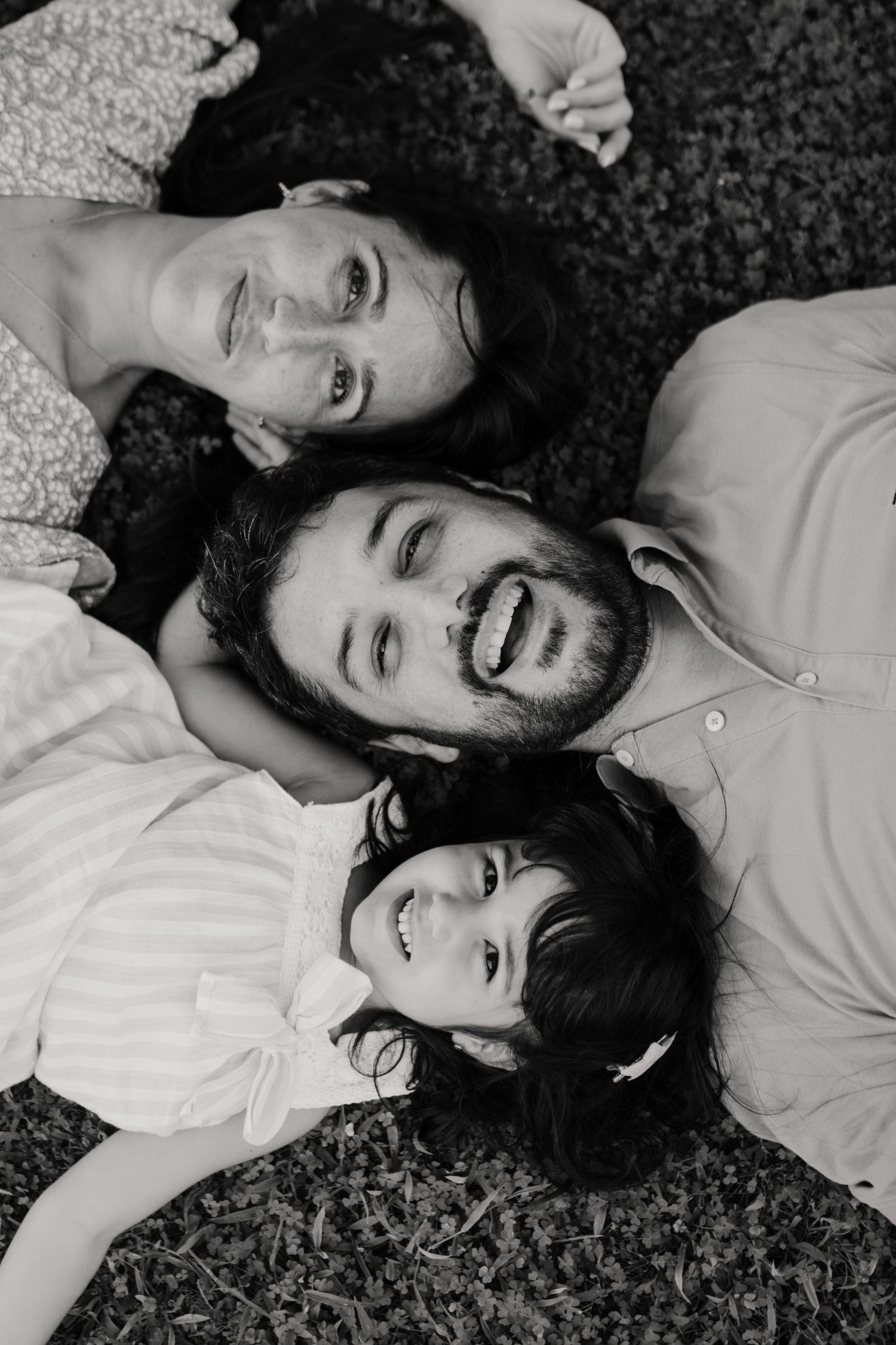 Padre, madre e hija mirando hacia arriba en fotografía familiar en blanco y negro en Tarragona