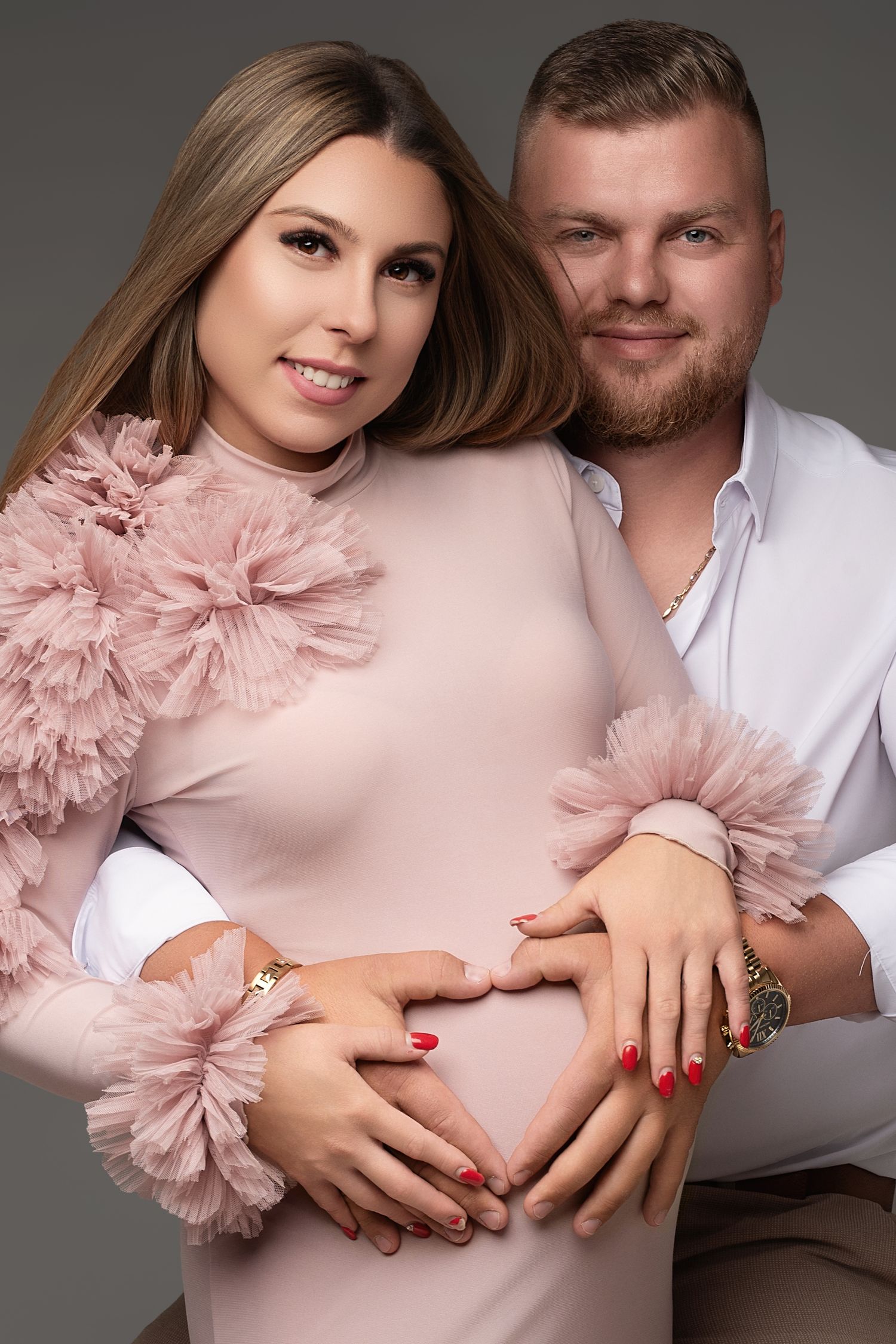 Közeli páros kismama portré: várandós nő rózsaszín tüllruhában, a pár keze a pocakon, Debrecen