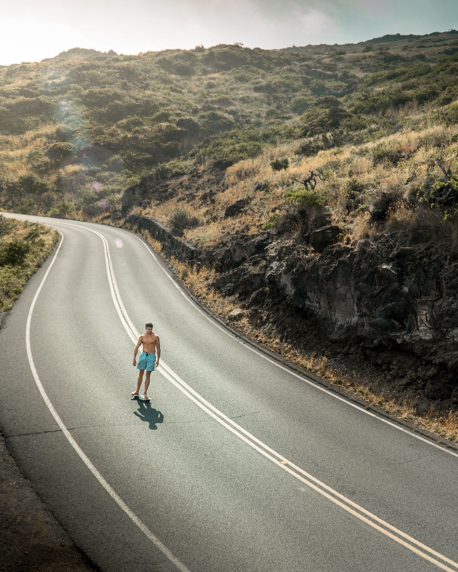 Downhill longboarding sequence on a curved mountain road during sunset.