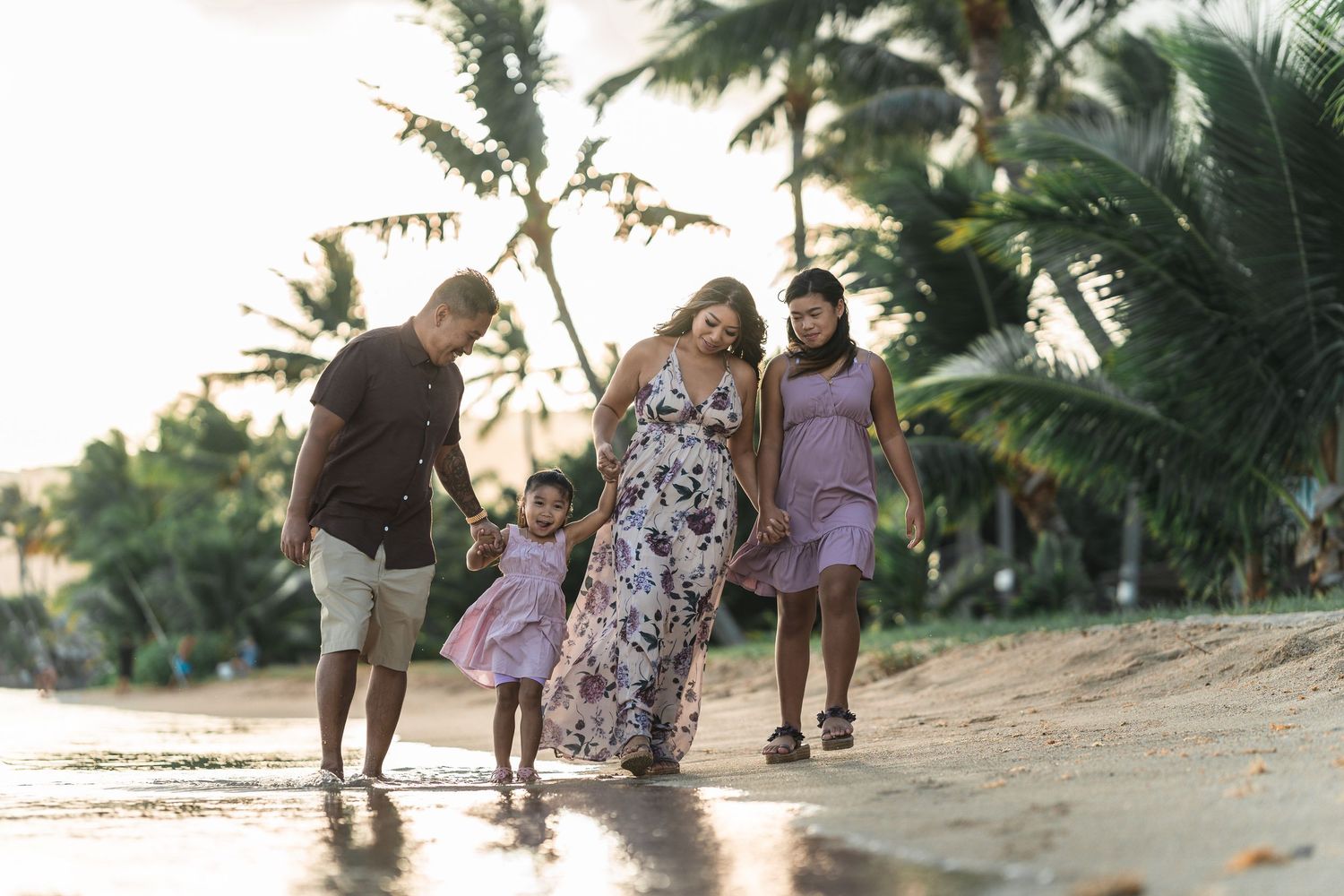 Family enjoying a sunset beach walk together in tropical Hawaii.