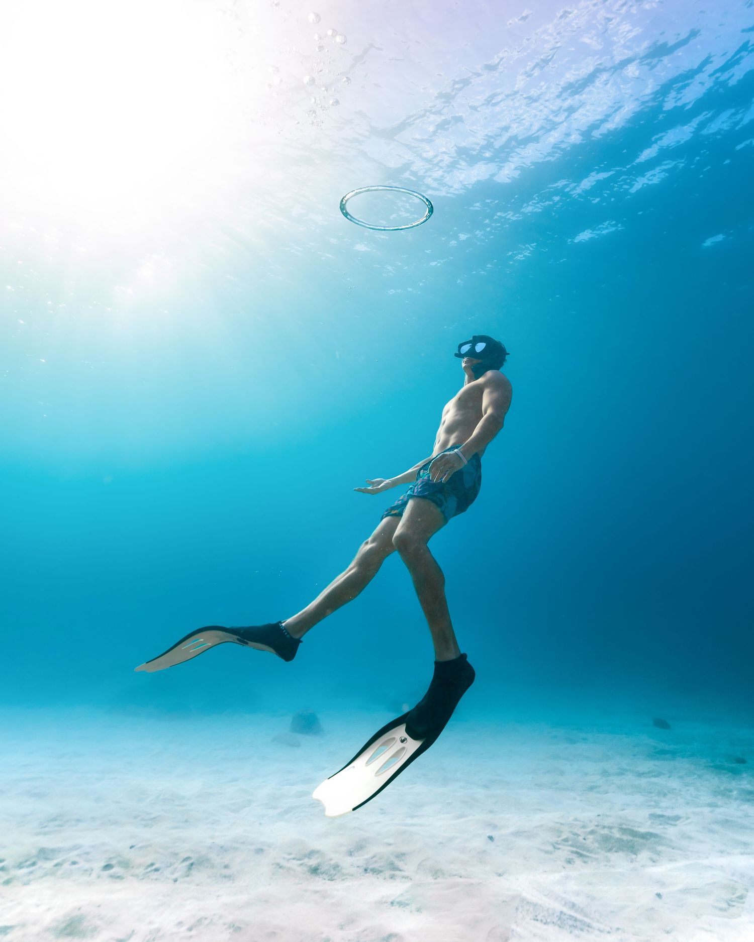 Underwater view of a swimmer gracefully gliding through crystal clear turquoise waters.