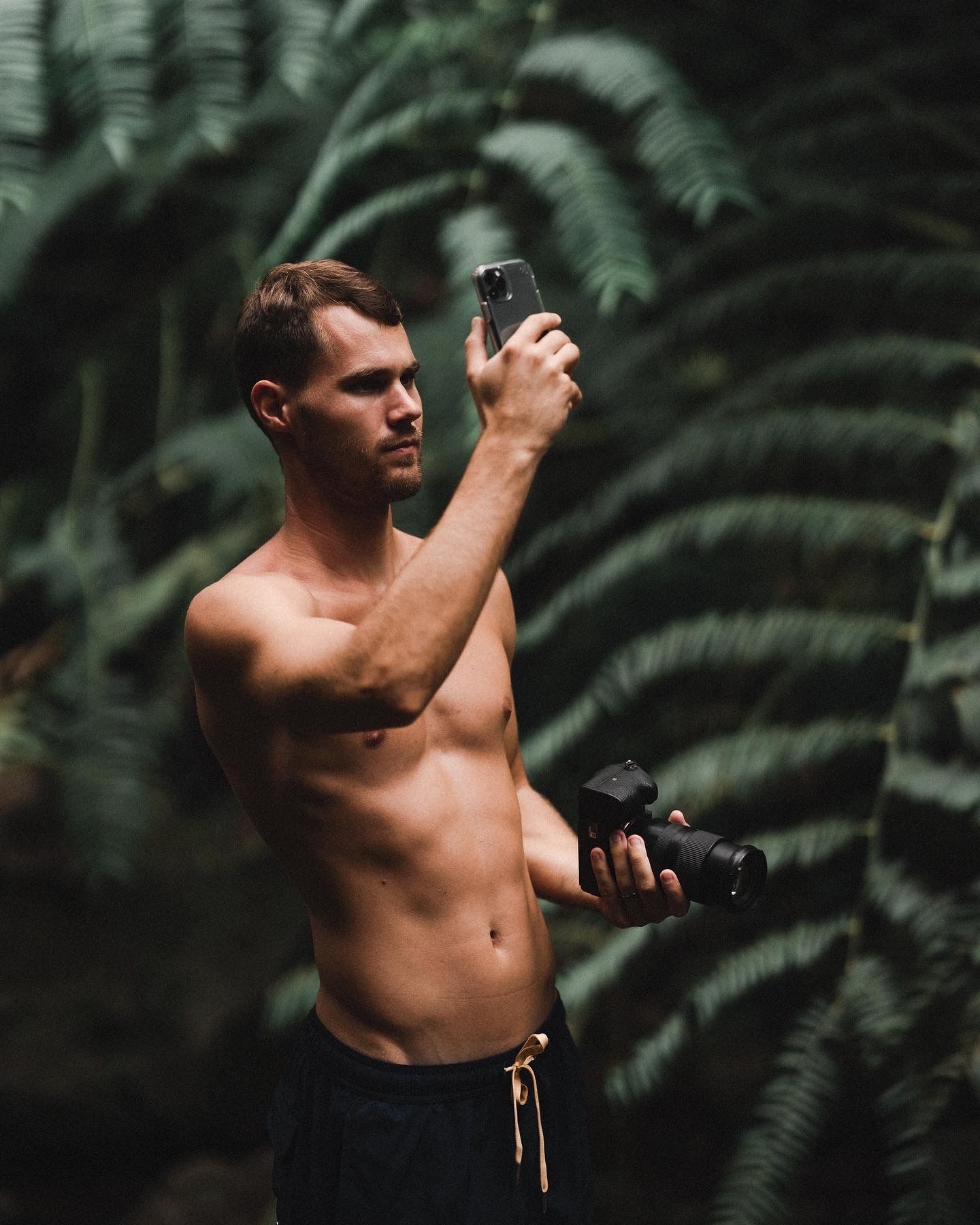 Camera equipment being adjusted in a tropical forest setting.