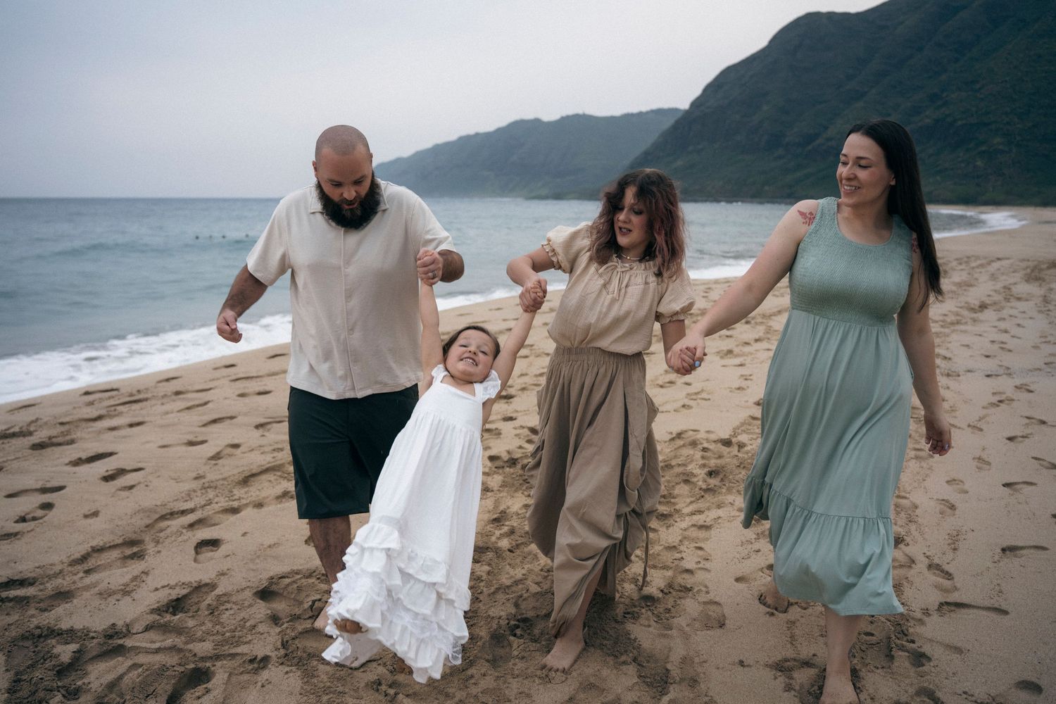 Group walking and playing together along the shoreline of a scenic Hawaiian beach.