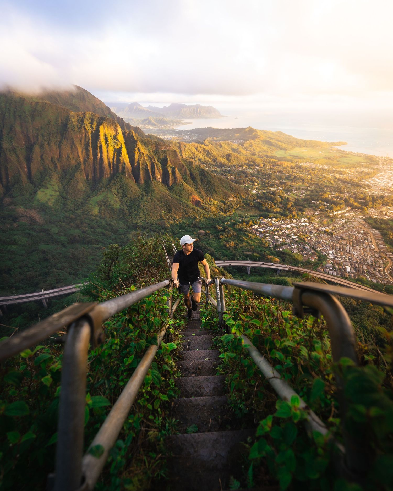 Steep hiking trail with railings leads to panoramic mountain views of a city nestled in the valley below.