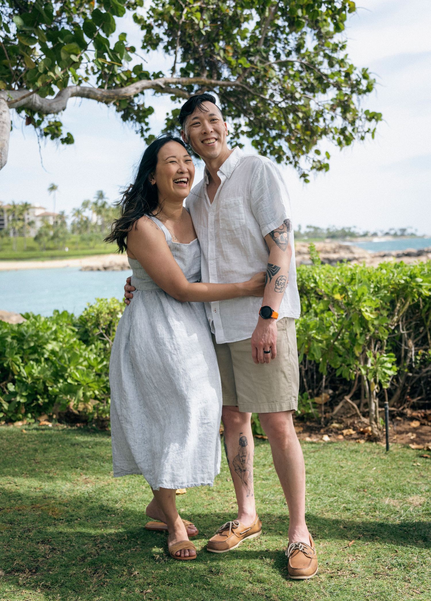 Couple sharing intimate moments on a lush green lawn overlooking the ocean.