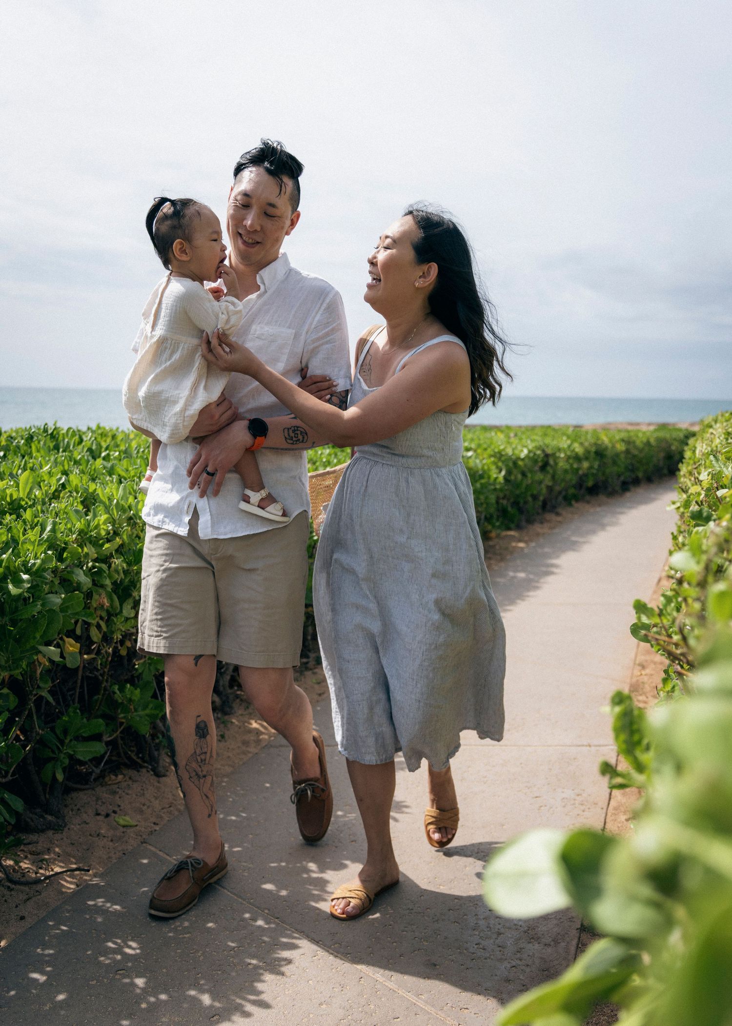 A family walks together and laughs on a coastal path with ocean views.
