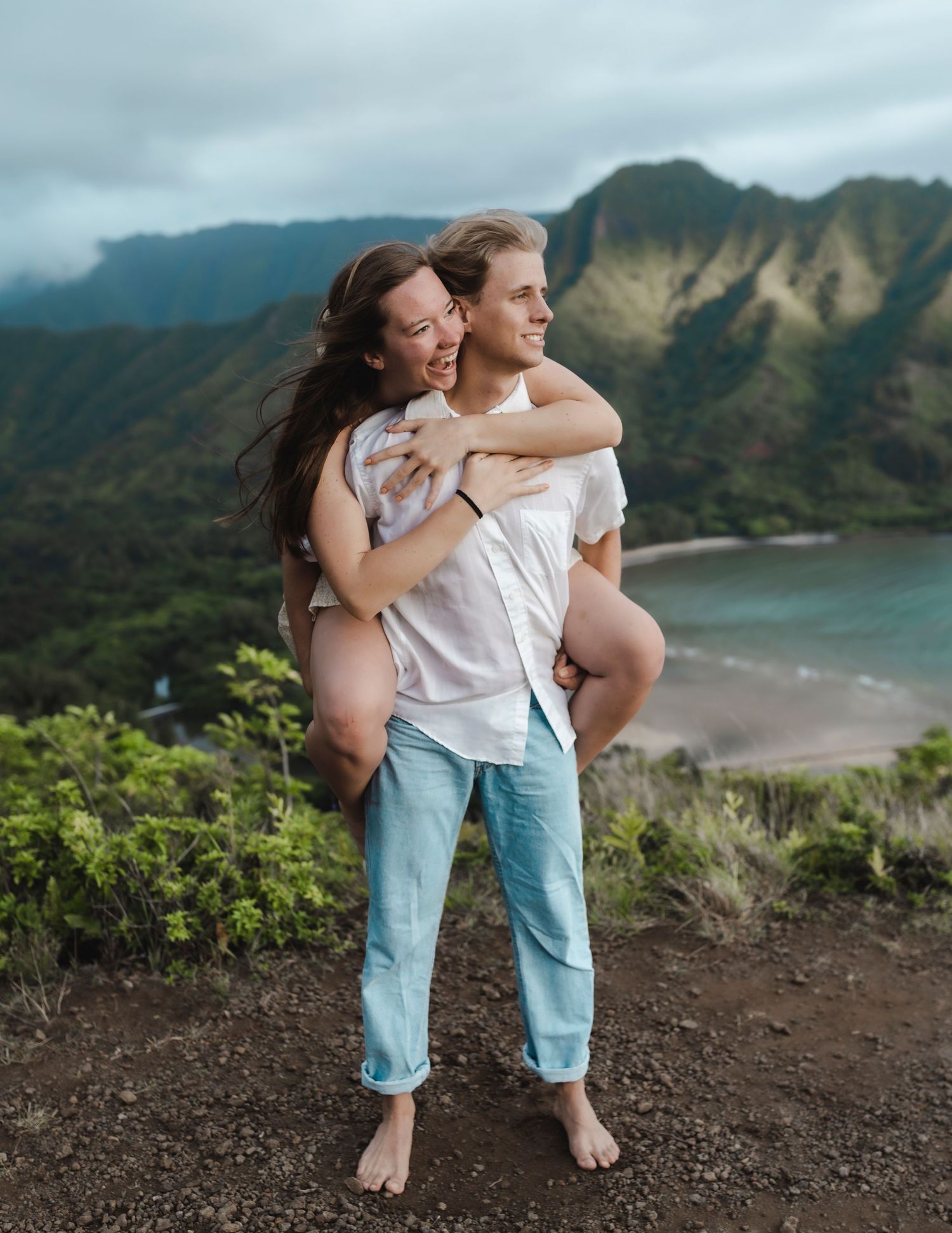 A romantic moment captured on a mountain overlook with dramatic coastal views of Hawaii.