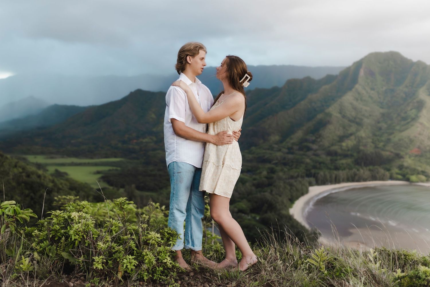 Couple enjoying scenic mountain views overlooking a dramatic Hawaiian coastline.